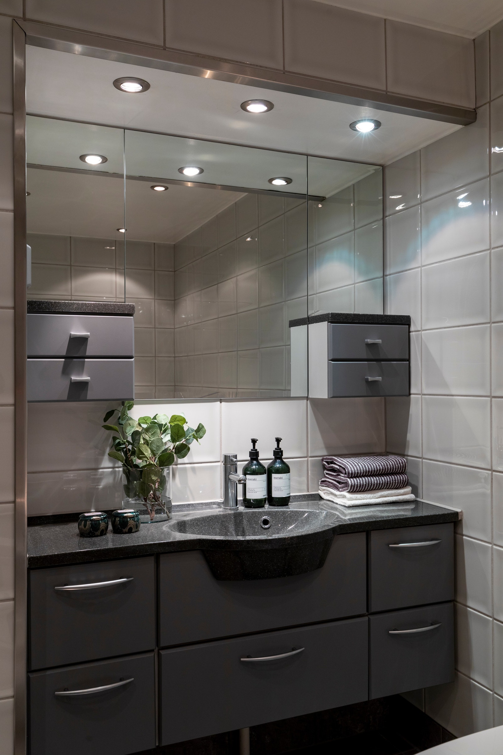 Servantskap med skuffer i innredning, samt speil, lys og stikkontakter over. Galleribilde