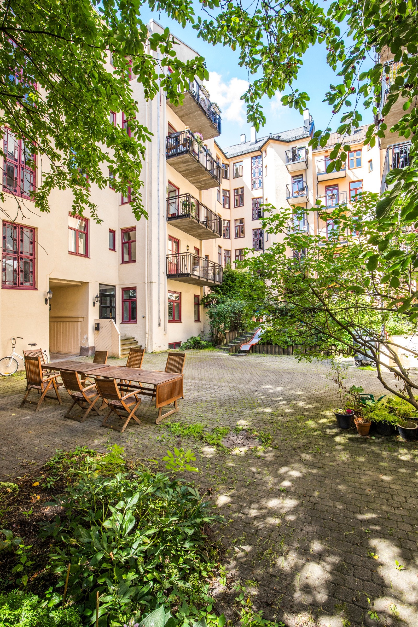 Skjermet, hellelagt bakgård med fin beplantning og sittegruppe til bruk for beboerne. Galleribilde