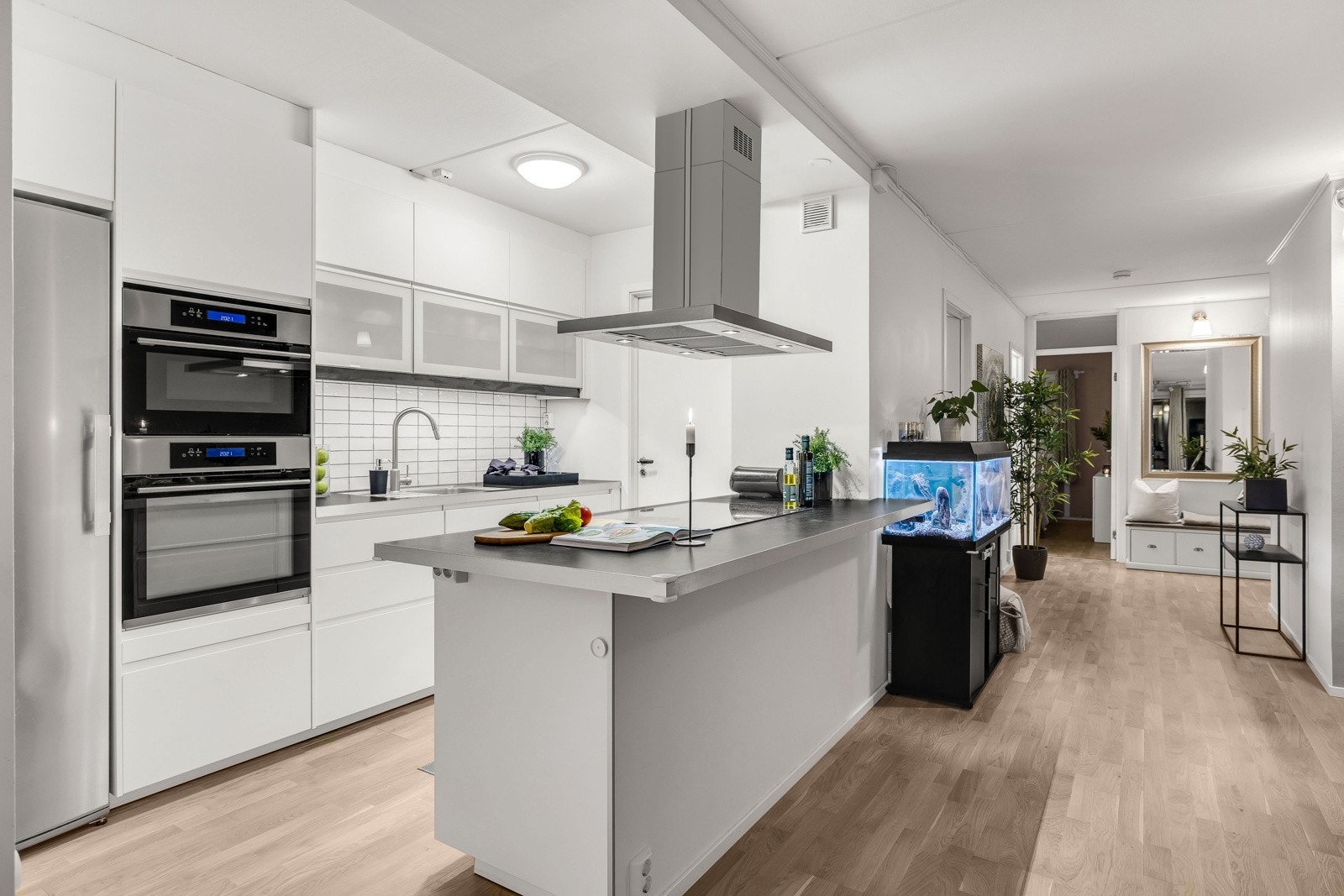 Kjøkkeninnredningen er fra Ikea og ble montert i 2015. Her er det hvite, håndtaksløse fronter, vitrineskap, laminert benkeplate og benkebeslag med oppvaskkum i rustfritt stål. Galleribilde