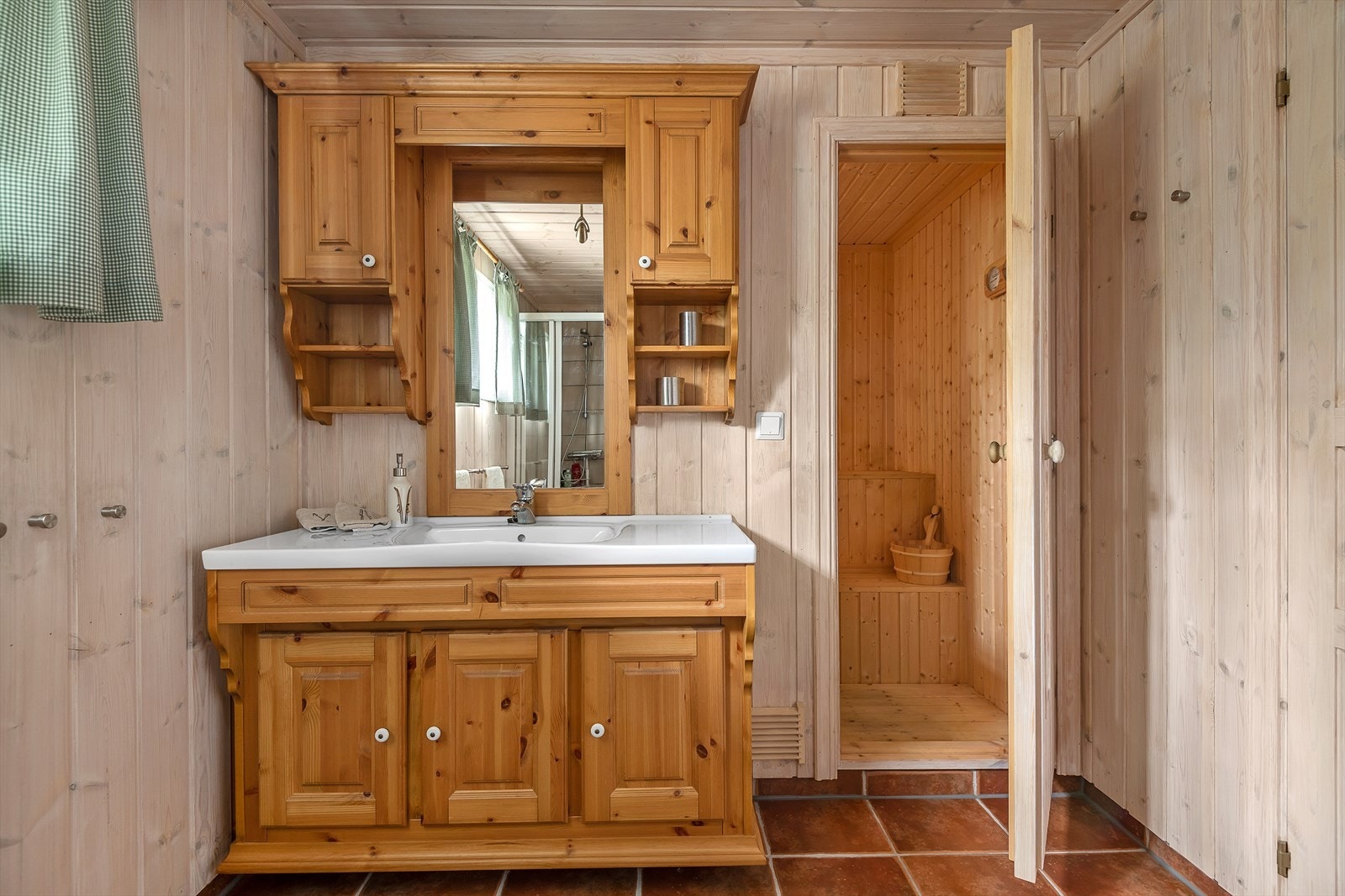 Lunt, pent og funksjonelt bad/wc. Flislagt gulv med varmekabler og panelte vegger og tak. Servantinnredning med skap for oppbevaring. Galleribilde