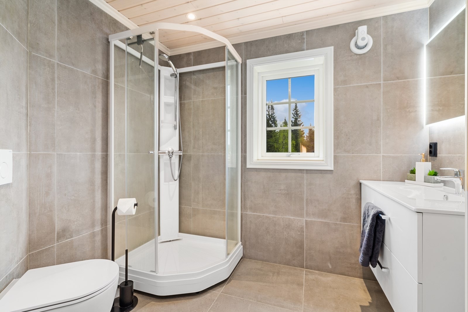 Her er det innredet med helstøpt servant på skuffeinnredning, speil med integrert belysning, dusjkabinett, og vegghengt wc. Her er det også et praktisk vindu som sørger for naturlig lys og luftemuligheter. Galleribilde