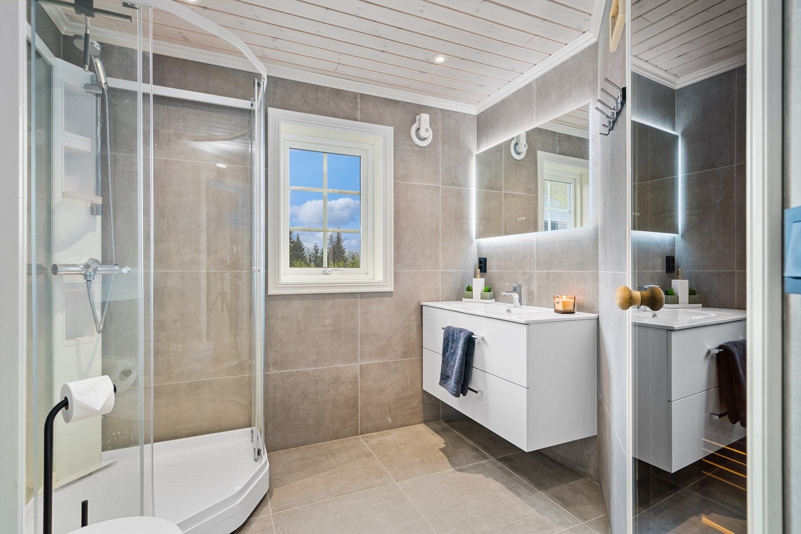 Pent og lyst bad i første etasje utført med lyse fliser, behagelig gulvvarme, og med hvit innredning. Galleribilde