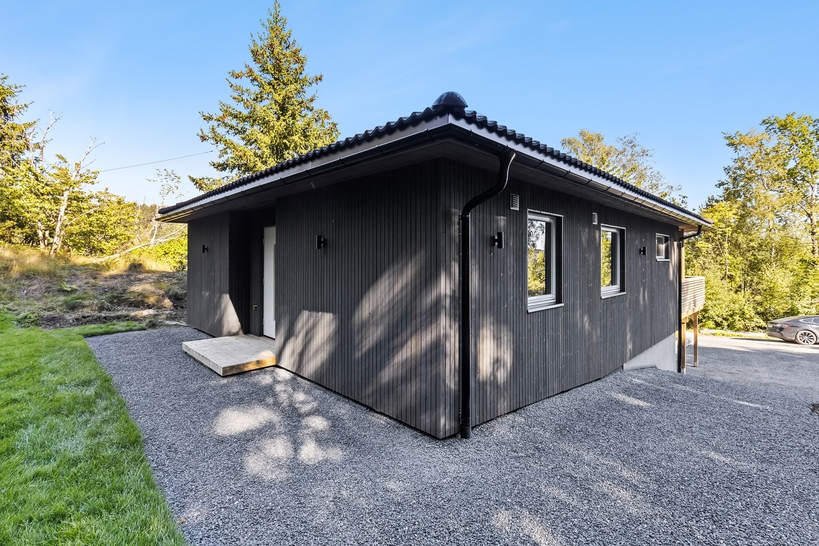 Tomten er opparbeidet med gruslagte partier, gressplen og diverse beplanting. Galleribilde