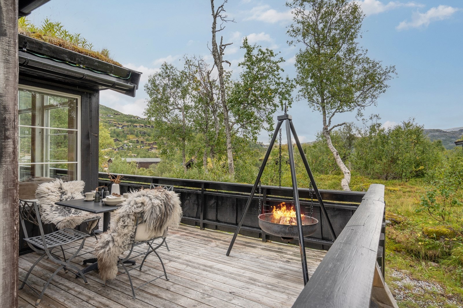 Stor funksjonell terrasse som strekker seg rundt to hele sider av hytten Galleribilde