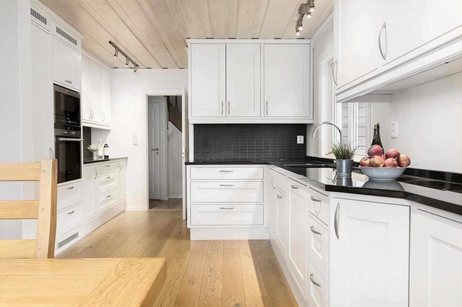 Kjøkkenet har en stilren innredning med profilerte, lyse fronter og benkeplate i svart granitt. Galleribilde