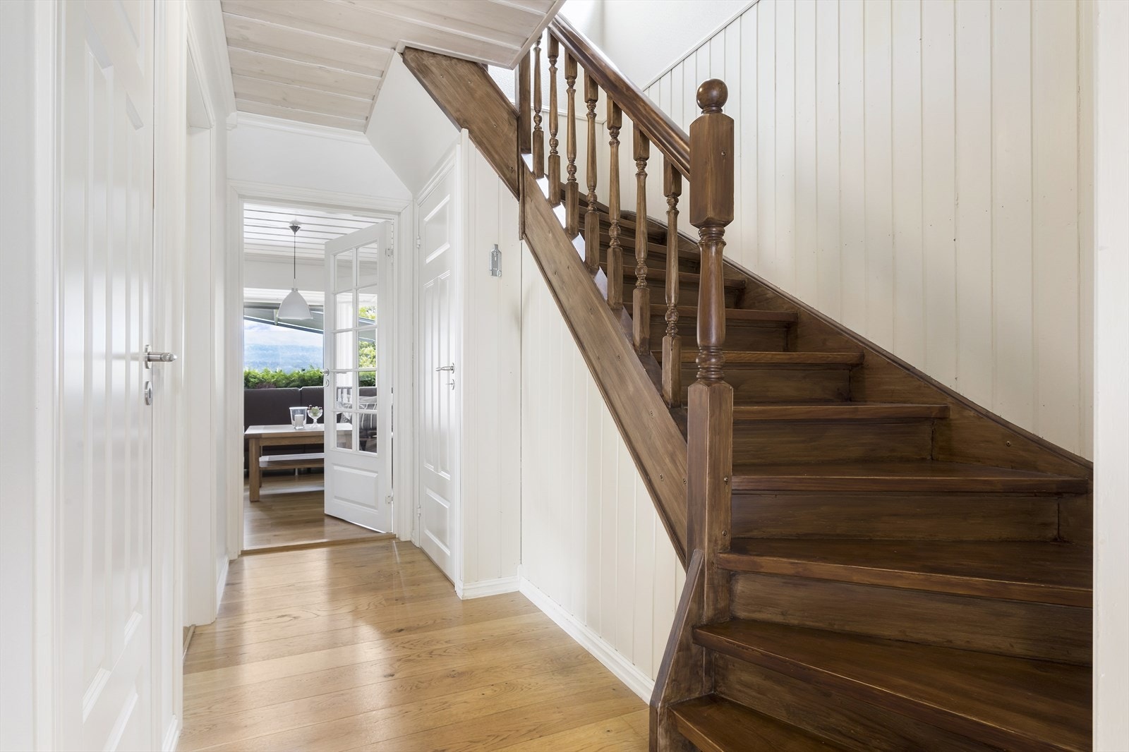 Innbydende trappehall med en-stavs eikeparkett og lysmalte overflater. Galleribilde