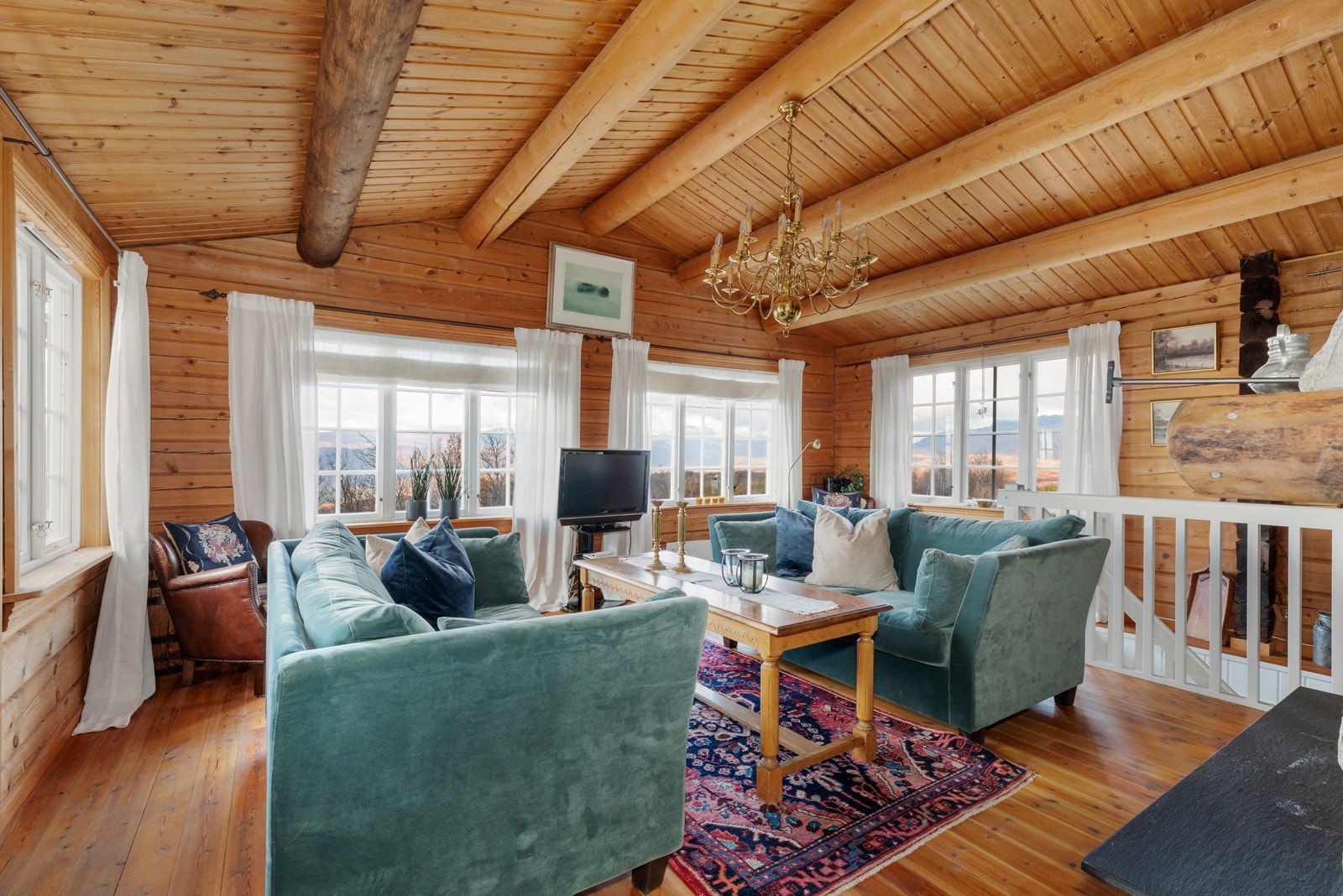 Stuen har en god takhøyde med synlige tømmeråser og store vindusflater som bidrar til et godt dagslys Galleribilde