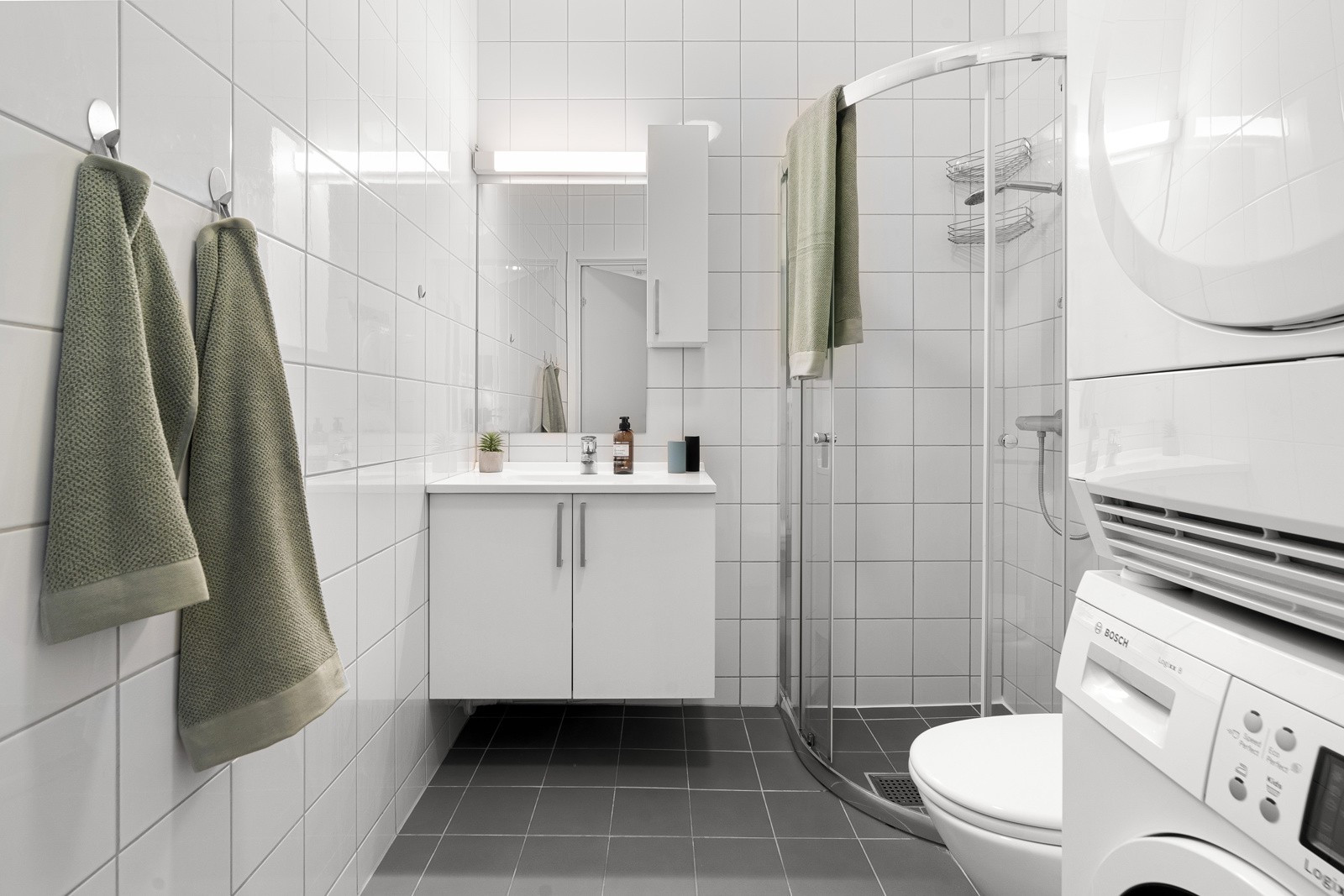 Romslig bad med lys innredning, overspeil med belysning og dusjhjørne.