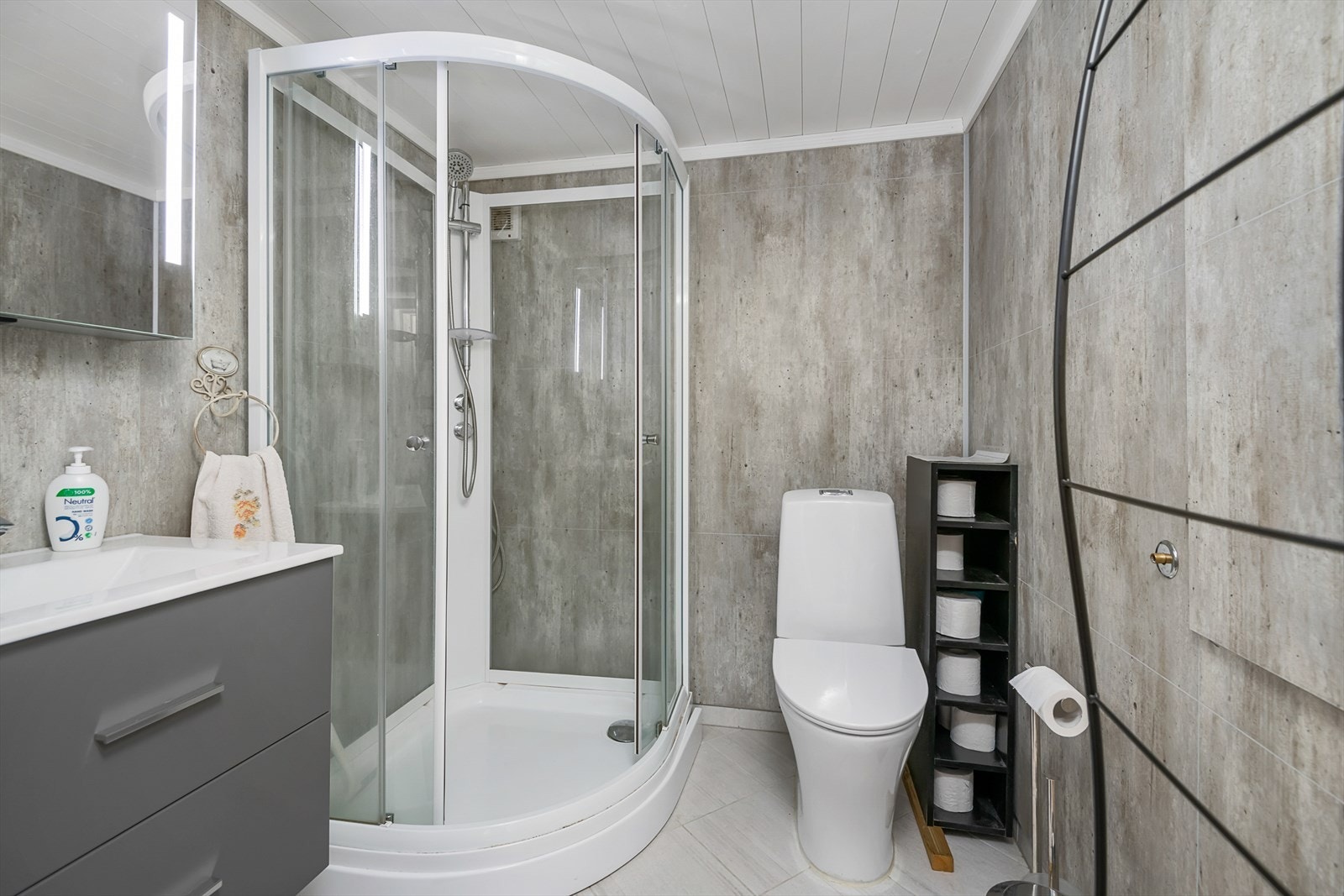 Pent og delikat bad/wc i underetasjen på hovedhytta. Servantinnredning og dusjkabinett. Galleribilde