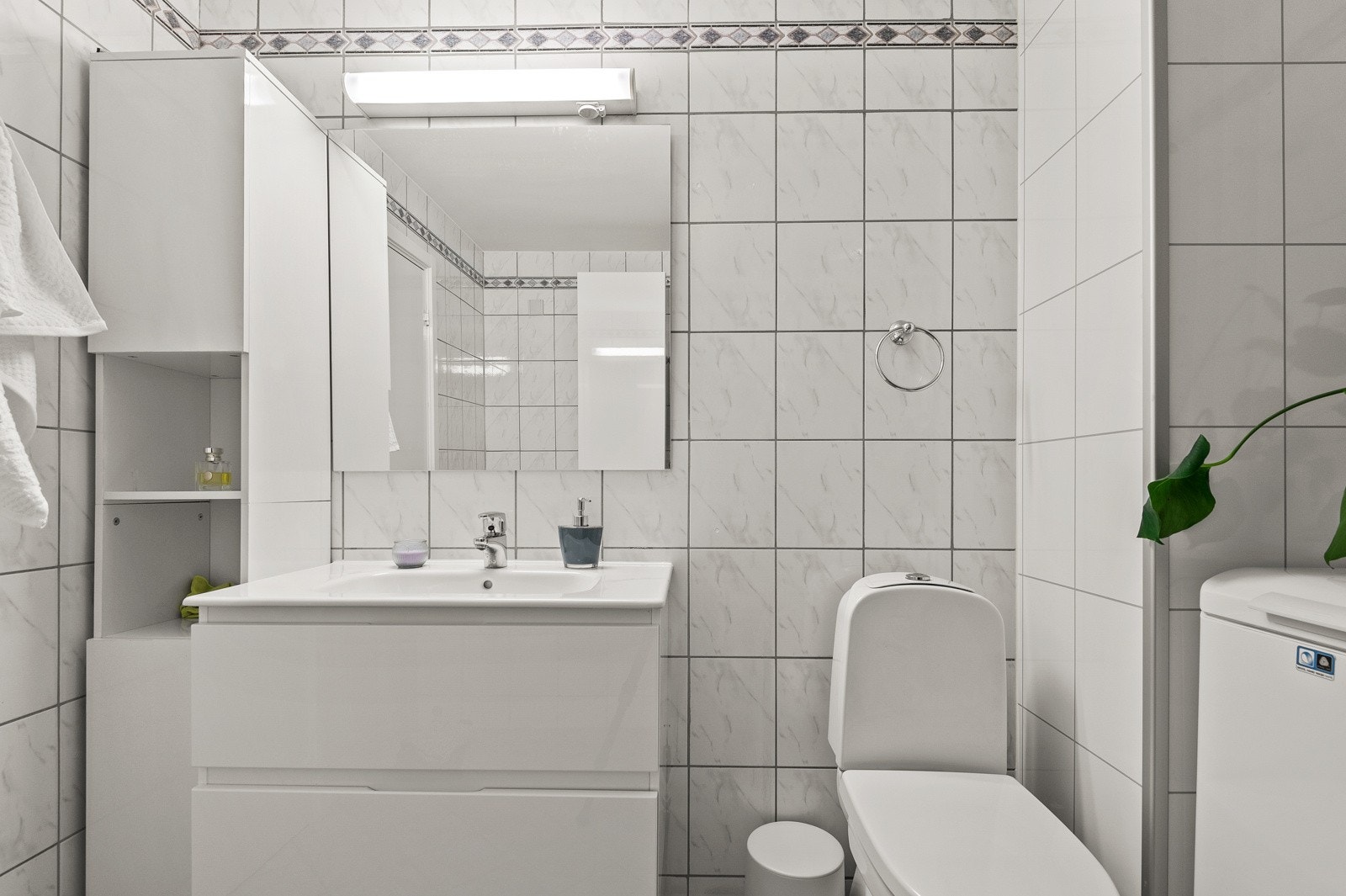 Inneholder heldekkende servant med skuffer, speil med belysning, 2 veggskap, dusjkabinett, klosett og opplegg for vaskemaskin. Galleribilde