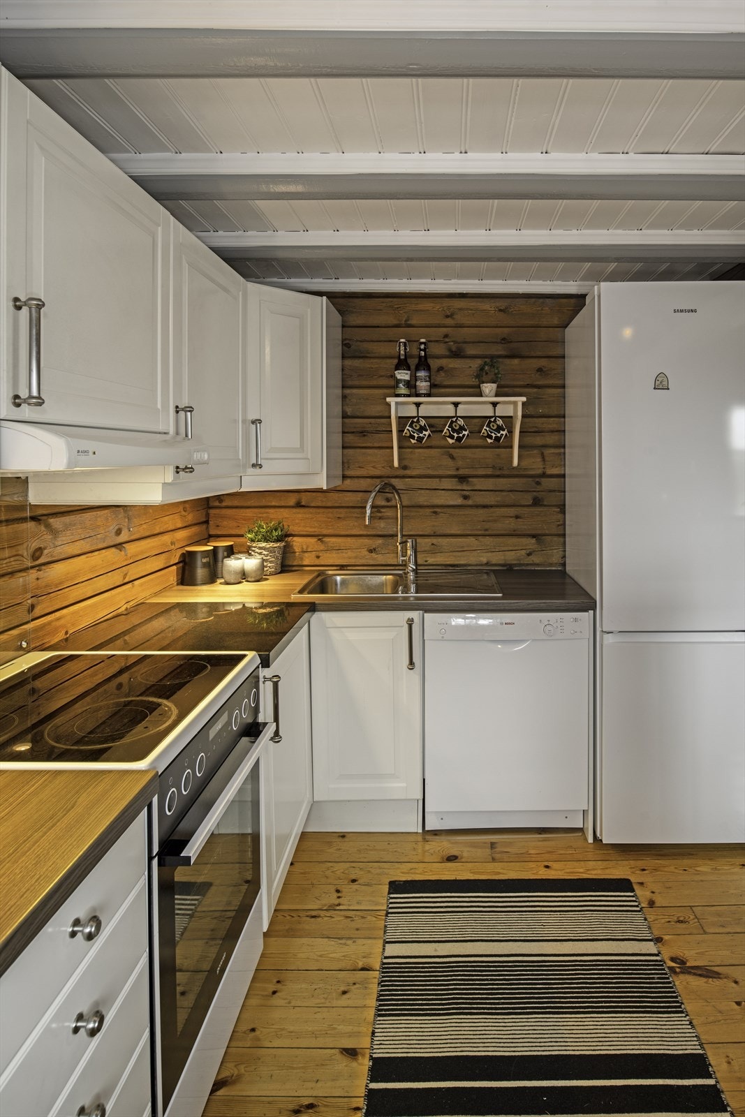 Kjøkkenet har åpen løsning for hvitevarer, profilerte fronter og stålkum med ett-greps kran Galleribilde