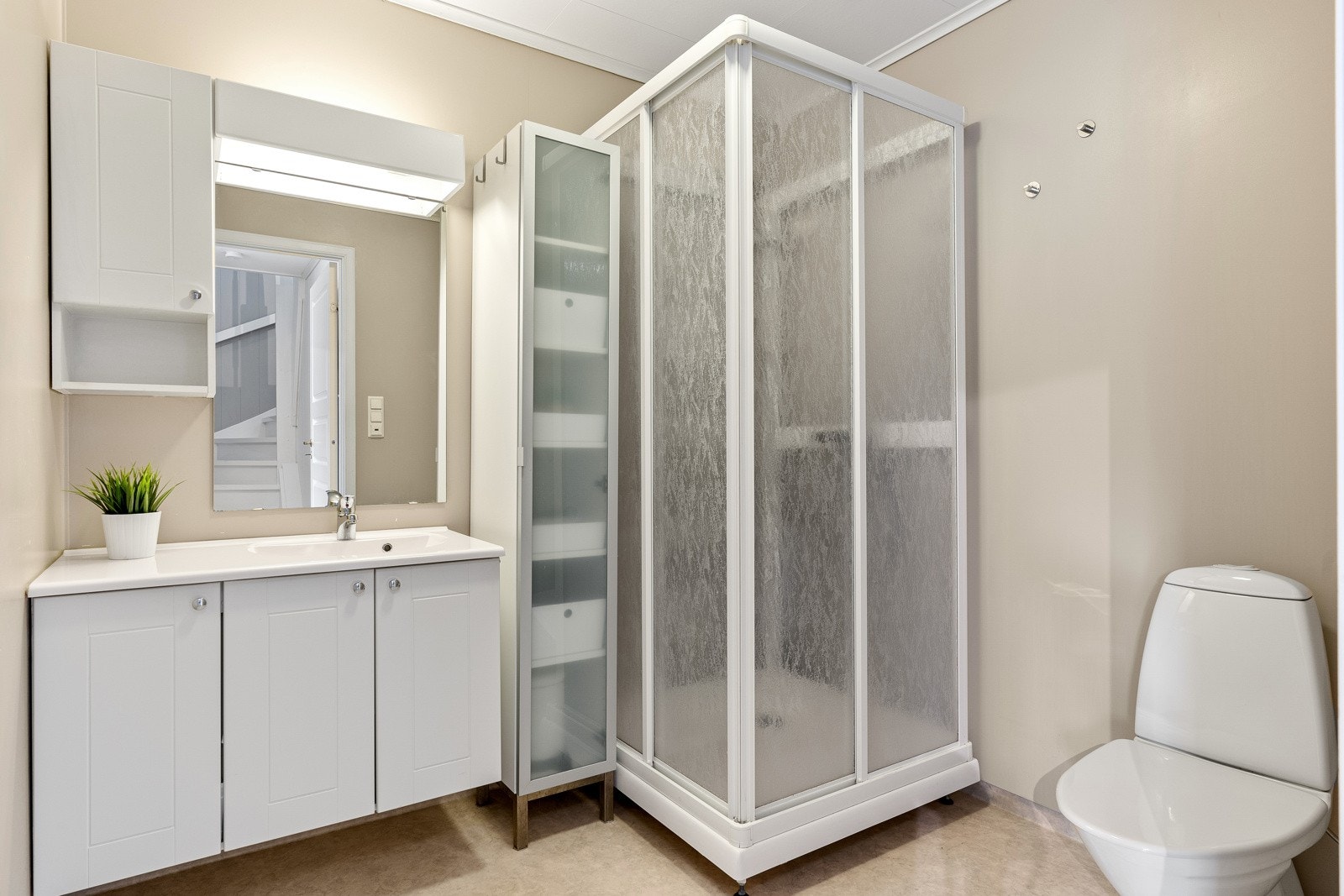 Tidløst baderom, innredet med servantmøbel, dusjkabinett og toalett. Separat vaskerom for vask/tørk. Galleribilde