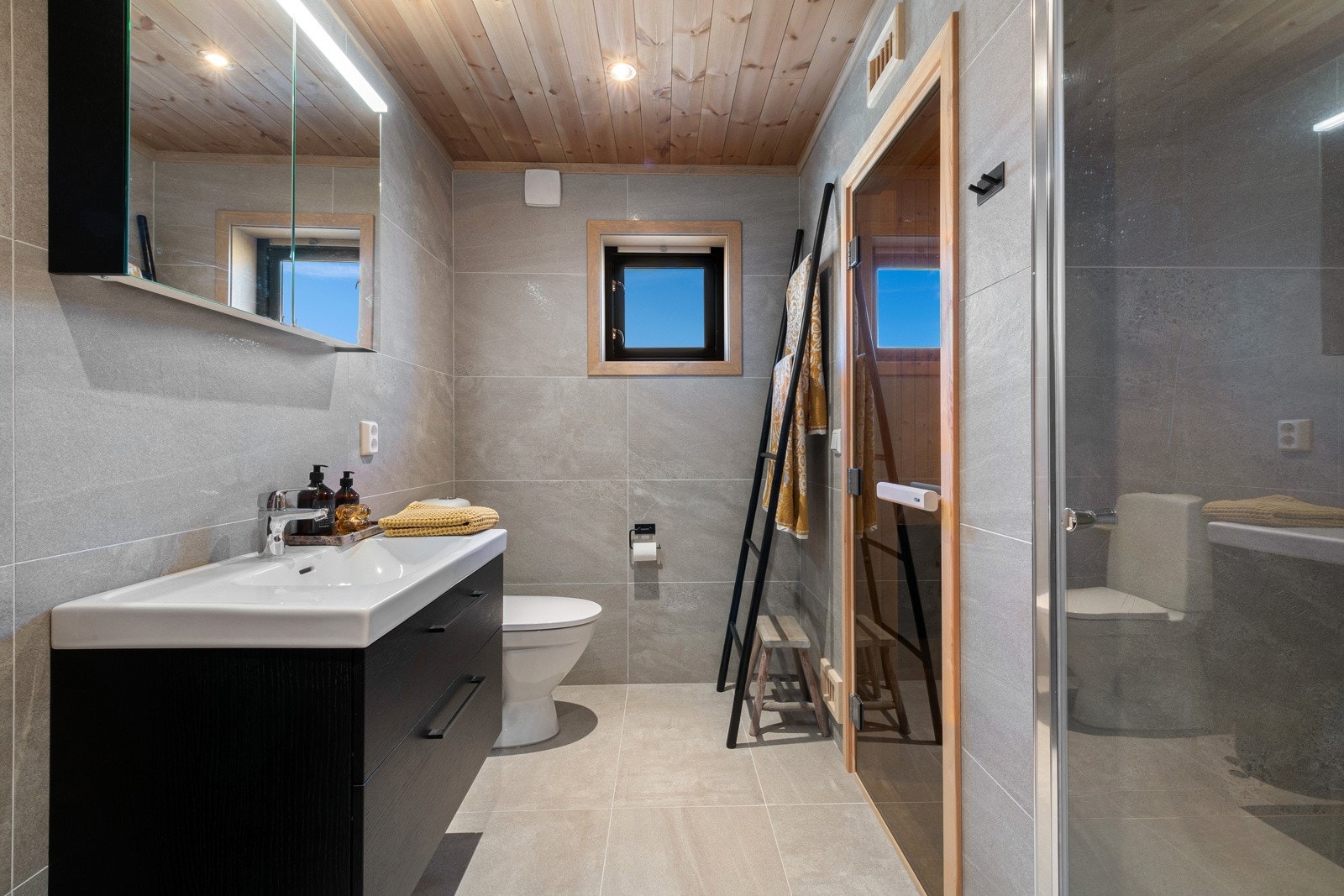 Baderomsinnredningen består av et sort skuffemøblement med heldekkende servant, og over er det dobbelt speilskap. Galleribilde