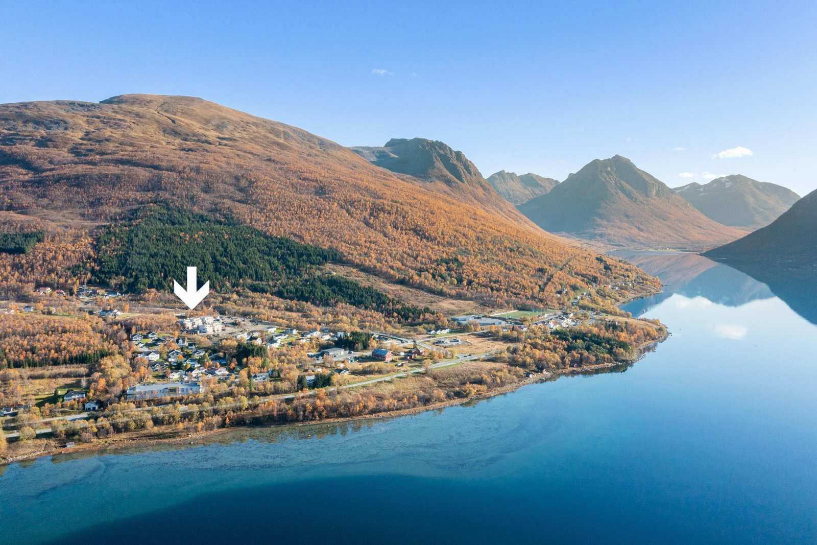 Områdefoto. Bak boligen ser du Fagerfjellet, et yndet mål for toppturinteresserte. I bildet ser du ogå barnehage, skole og fotballbane.