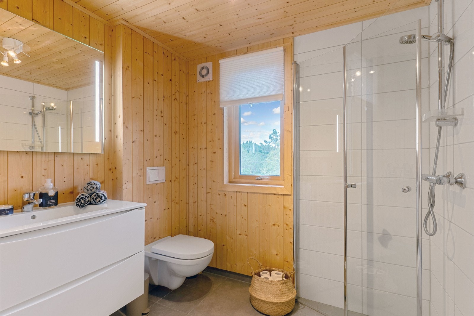 Baderom med våtromsplater i dusjsone, fliser på gulv og granpanel på veggene. Galleribilde