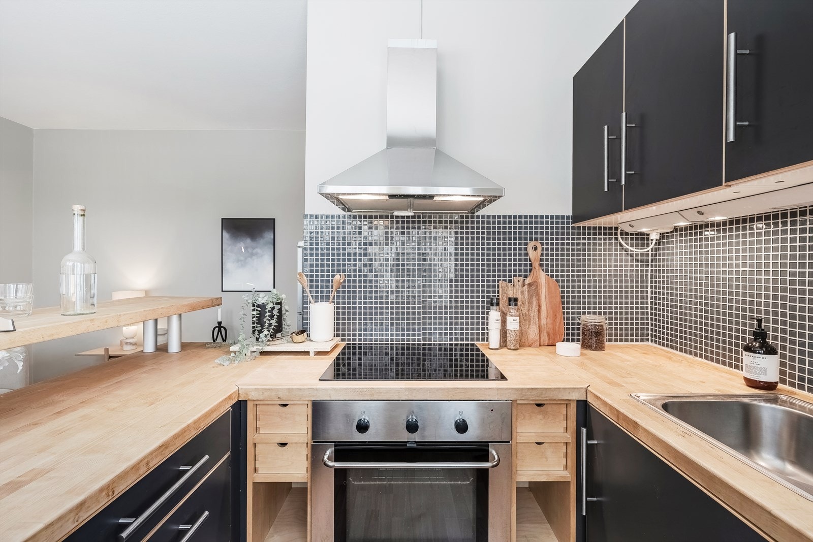 Kjøkkeninnredning består av sorte slette fronter og heltreplater som benkeplate. Galleribilde