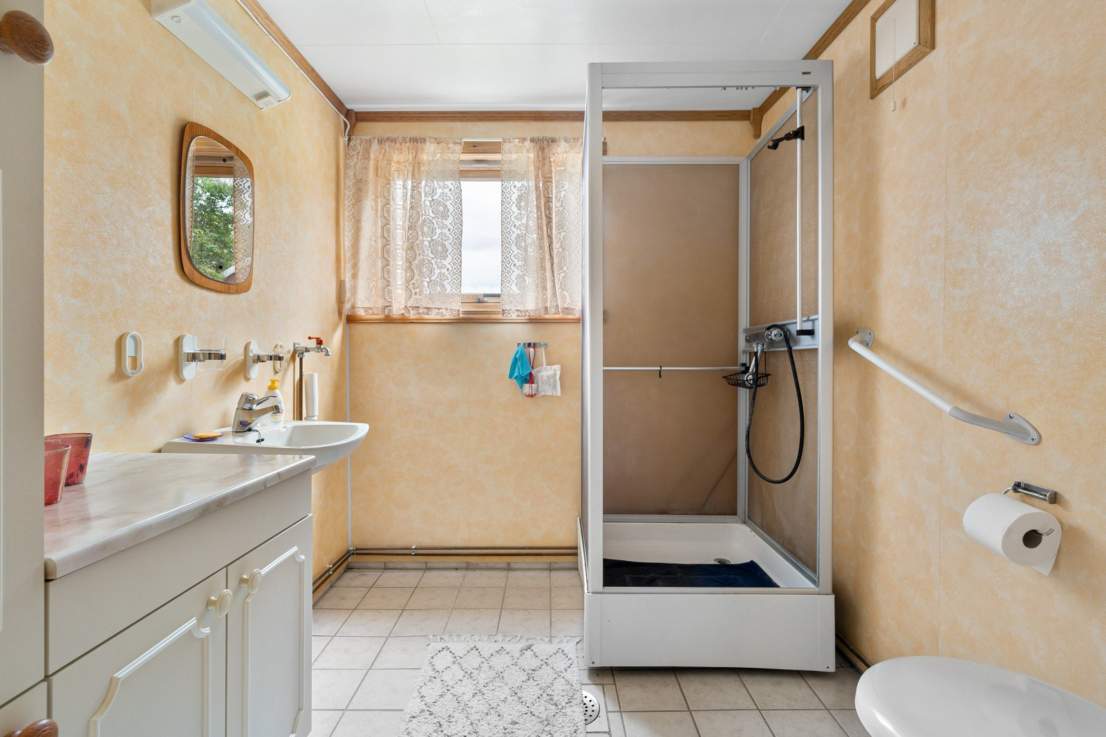 Badet har våtromspanel og flislagt gulv. Lys innredning med profilerte fronter med dørhåndtak.