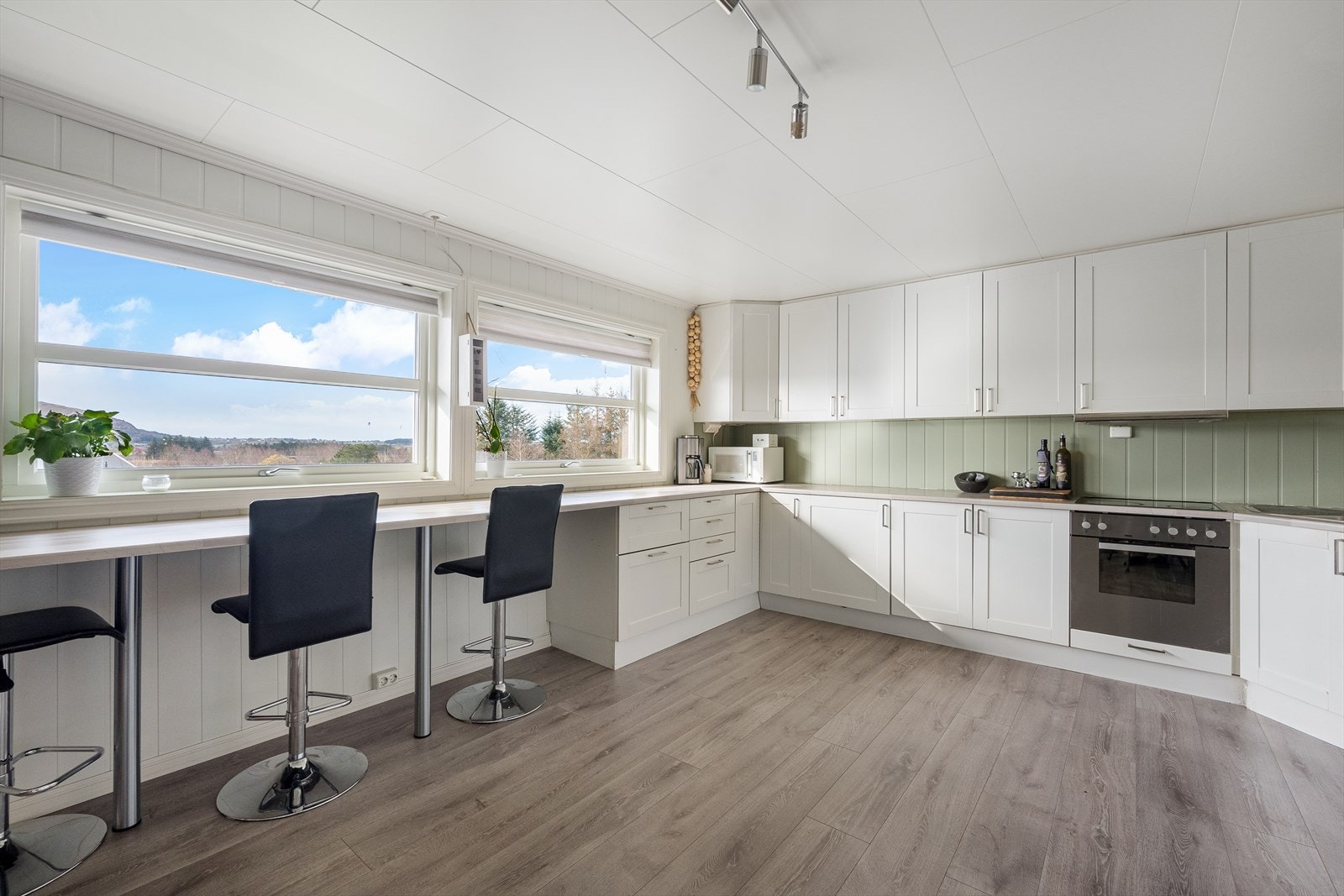 Lyst og romslig kjøkken med hvit kjøkkeninnredning. Galleribilde