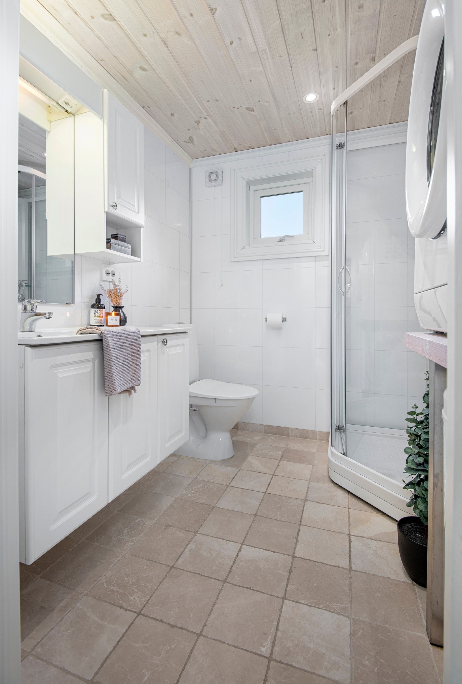Badet har fliser på gulvet og våtromsplater på veggene. Her er dusjkabinett, toalett, Galleribilde