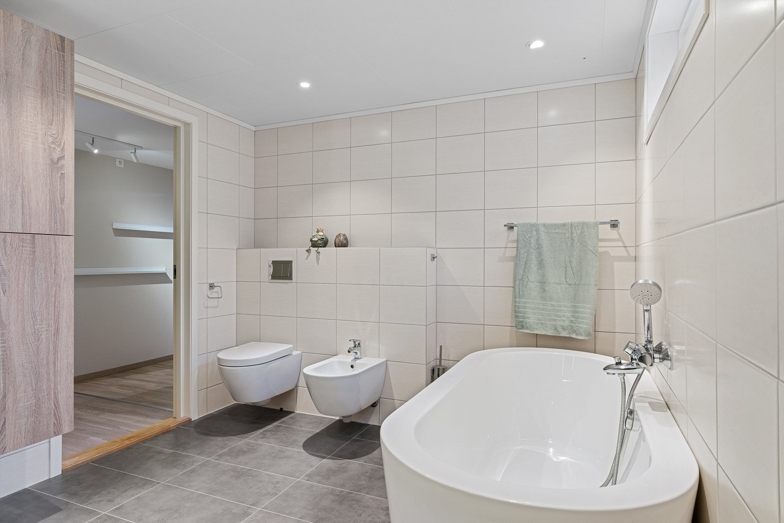 Badet er innredet med vegghengt wc, badekar, dusj, bidé og seksjon med vask. Gulvvarme Galleribilde