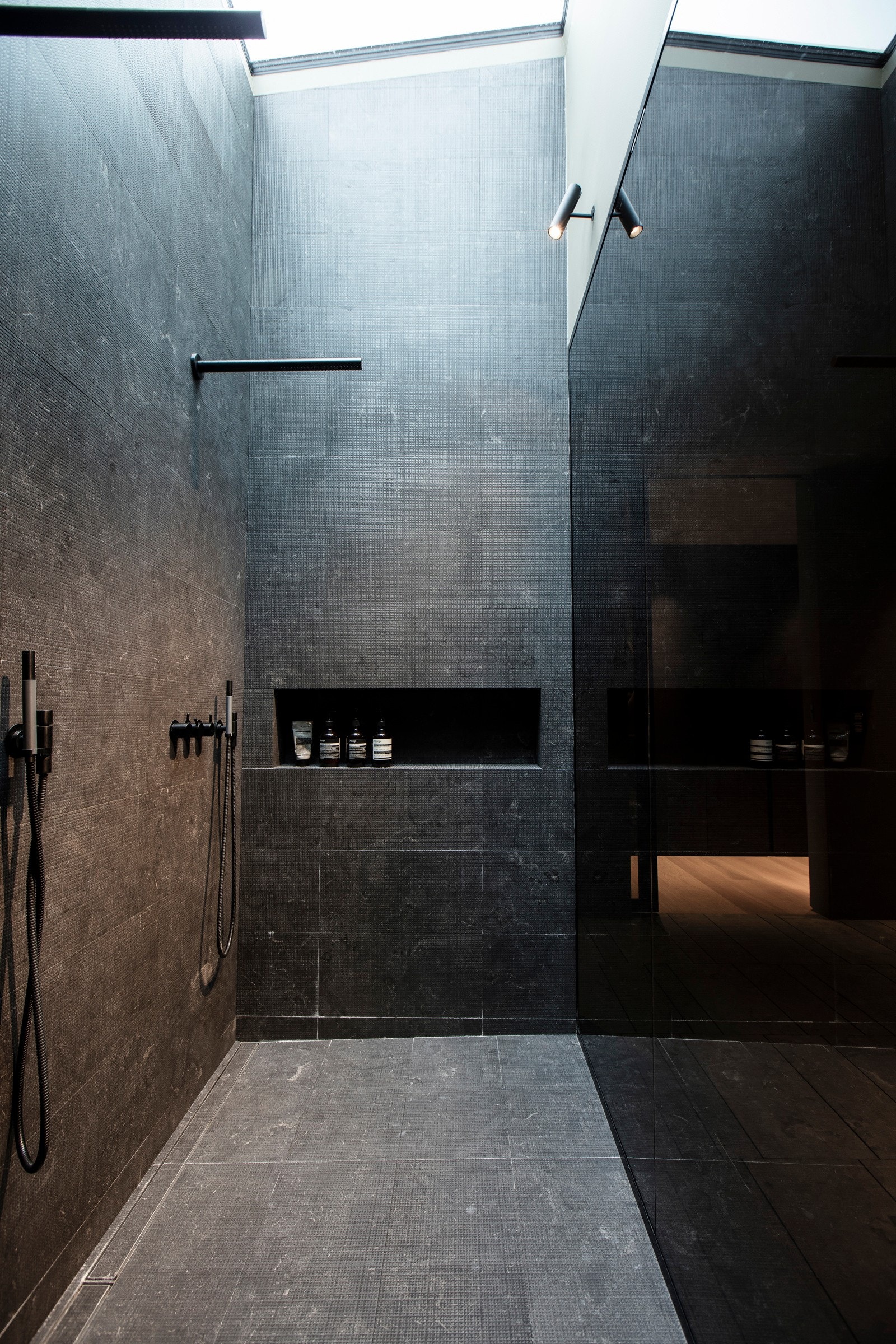 På gulvet er det lyse fliser og vannbåren varme, og i en stor dusjnisje er det mørkegrå fliser og naturlig lysinnslipp fra et takvindu. Galleribilde