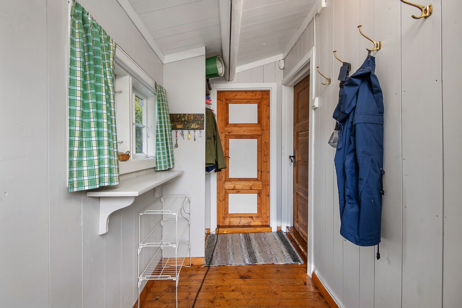 Gang med plass til å henge fra seg yttertøy og utstyr. Malt i lyse farger. Galleribilde