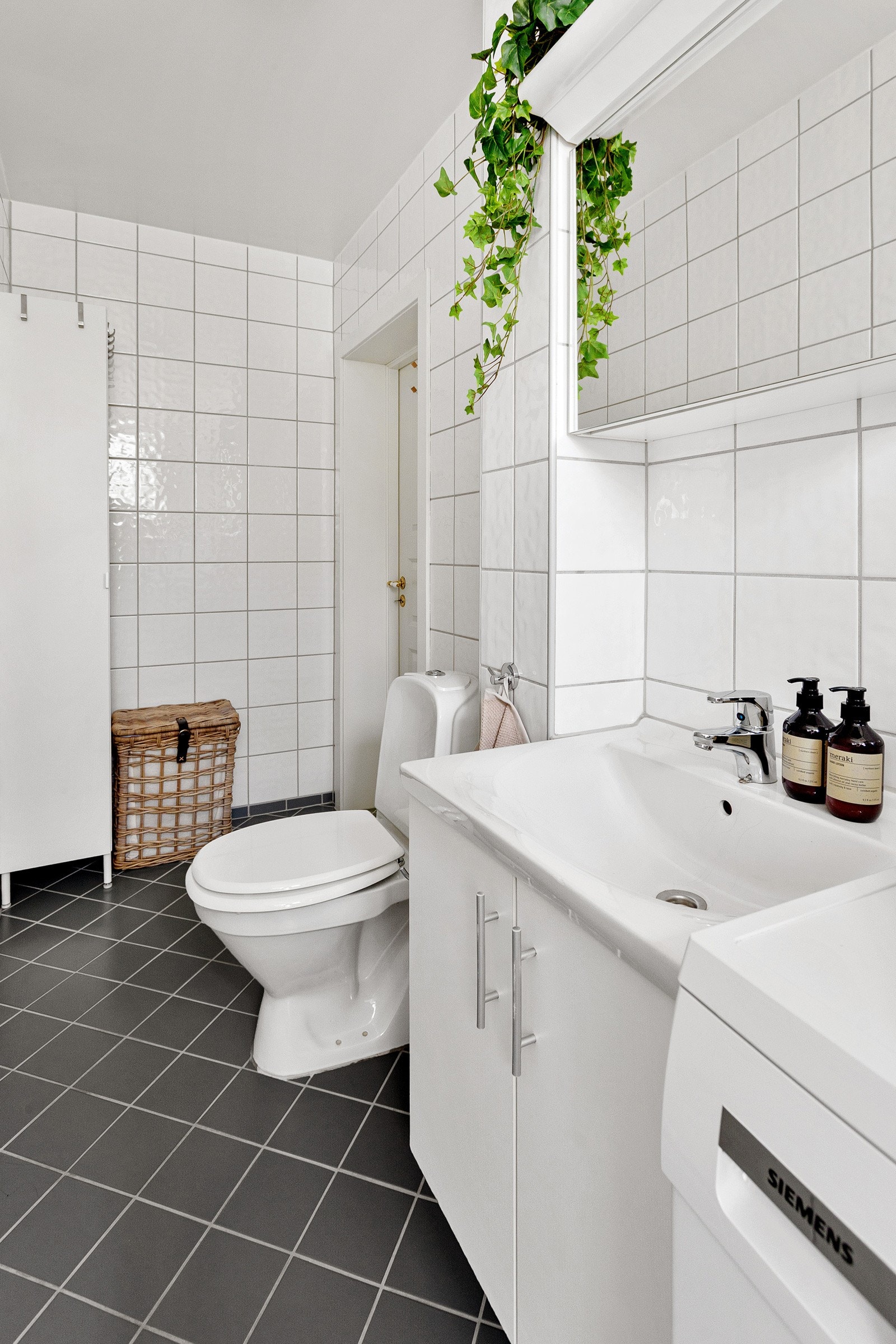 Badet har flislafgte overflater, toalett, servant med skap og speil og opplegg for vaskemaskin/tørketrommel. Galleribilde