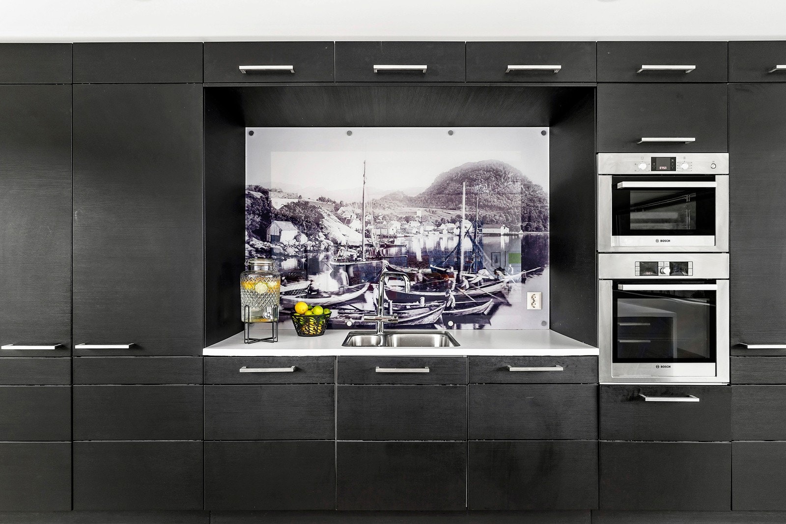 På veggen over vasken har man et eldre bilde fra Hjelmelandsvågen tatt ca 1895 med utsikt opp mot denne eiendommen ( tomten). Galleribilde