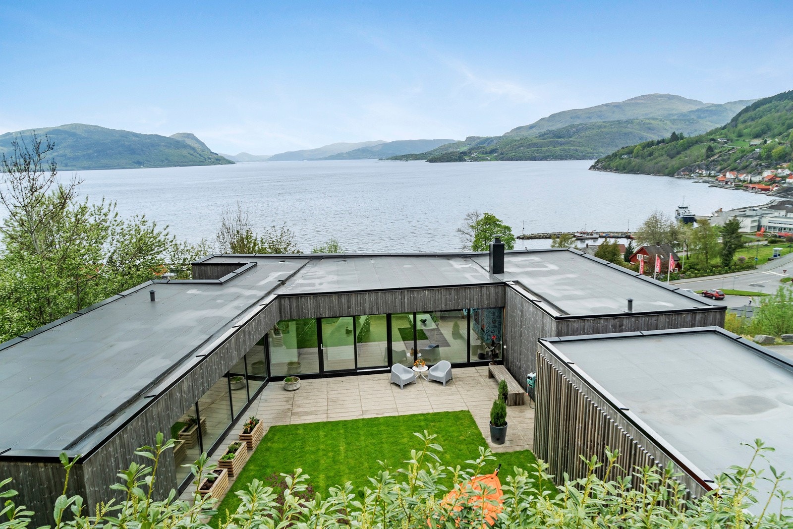 Atriumet er pent opparbeidet med plen, busker og trær, samt praktisk platting med betongheller langs boligen. Galleribilde