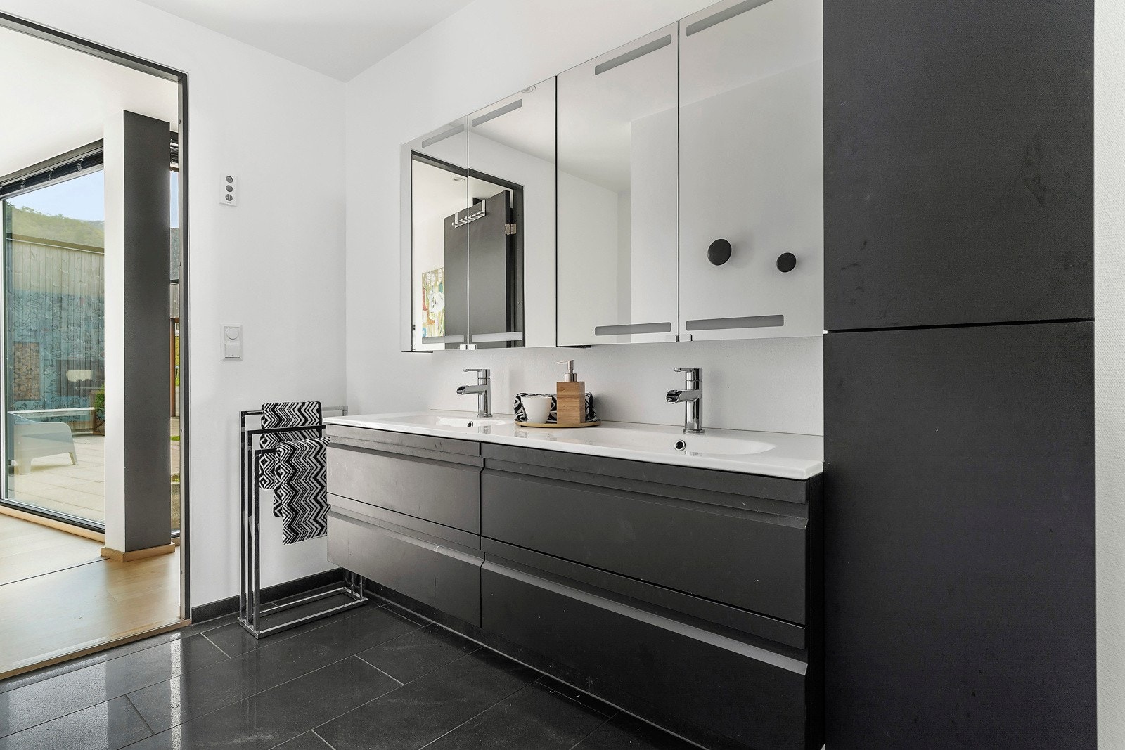 Badet i hovedetasjen har stilren innredning med sorte fliser på gulv Galleribilde