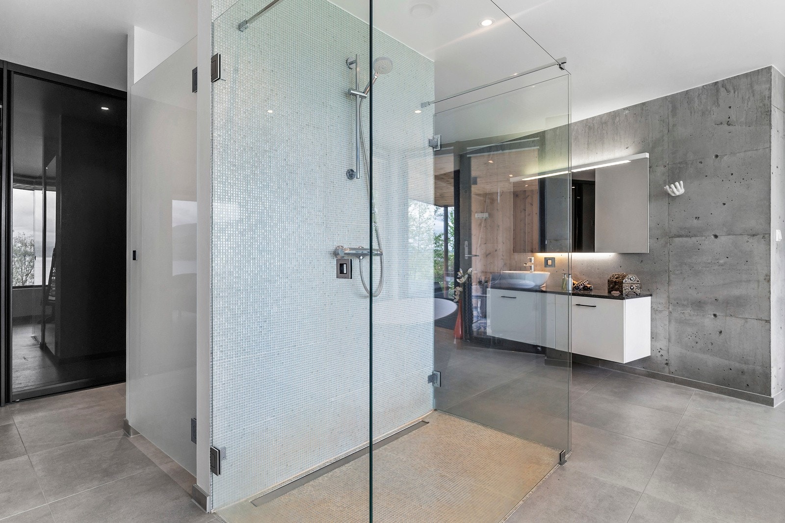 På badet her har man lekker dusj med skinnende mosaikkfliser plassert omtrent midt i rommet Galleribilde