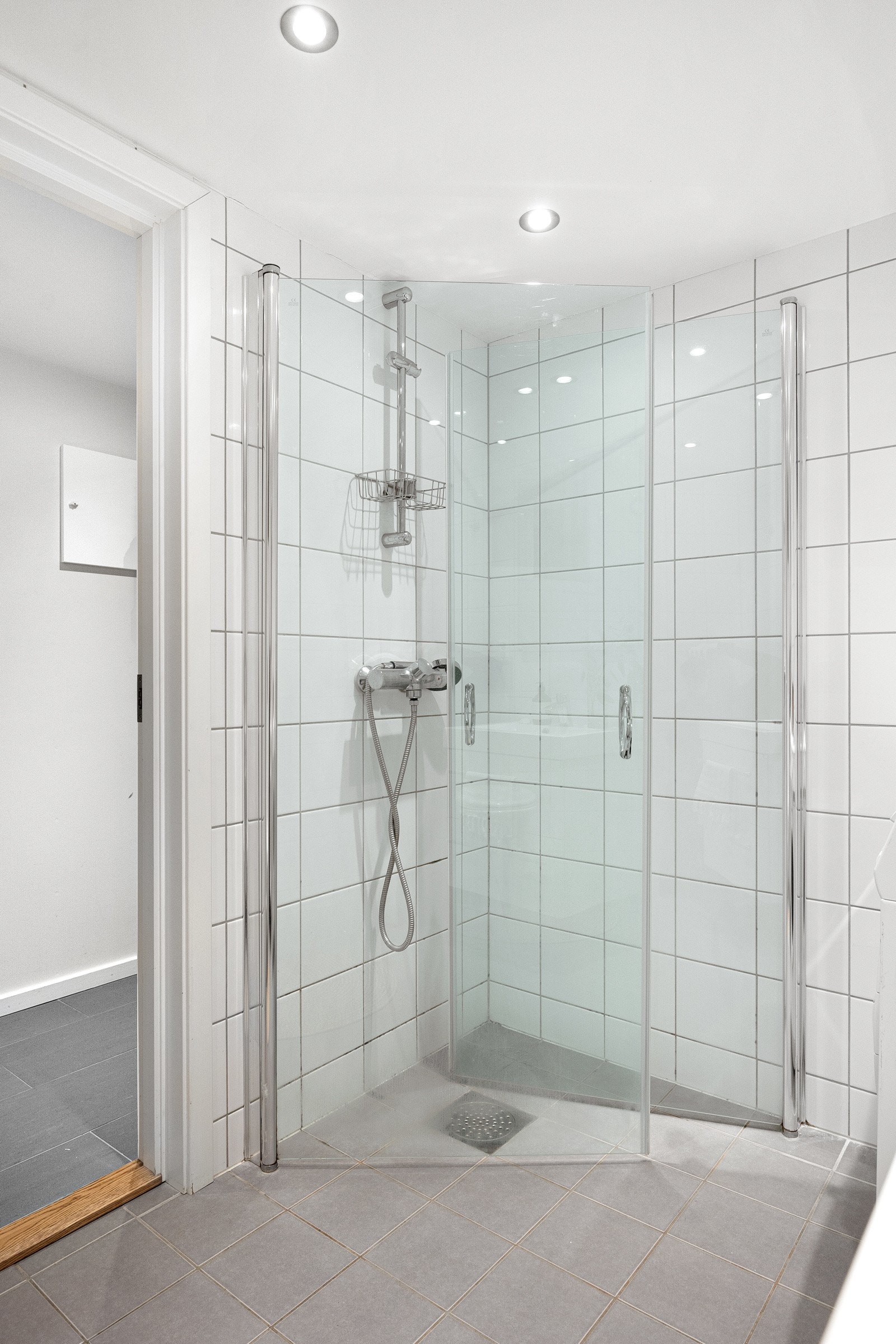 Badet har innredning bestående av enkel servant, dusjhjørne med svingbare glassdører og vegghengt toalett. Galleribilde