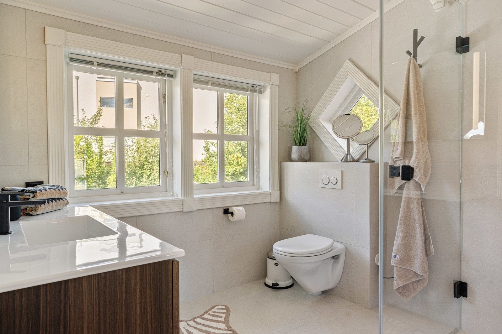 Badet er nytt, lyst og delikat, med flisbelagte gulv og vegger, veggmontert wc og dusj. Galleribilde