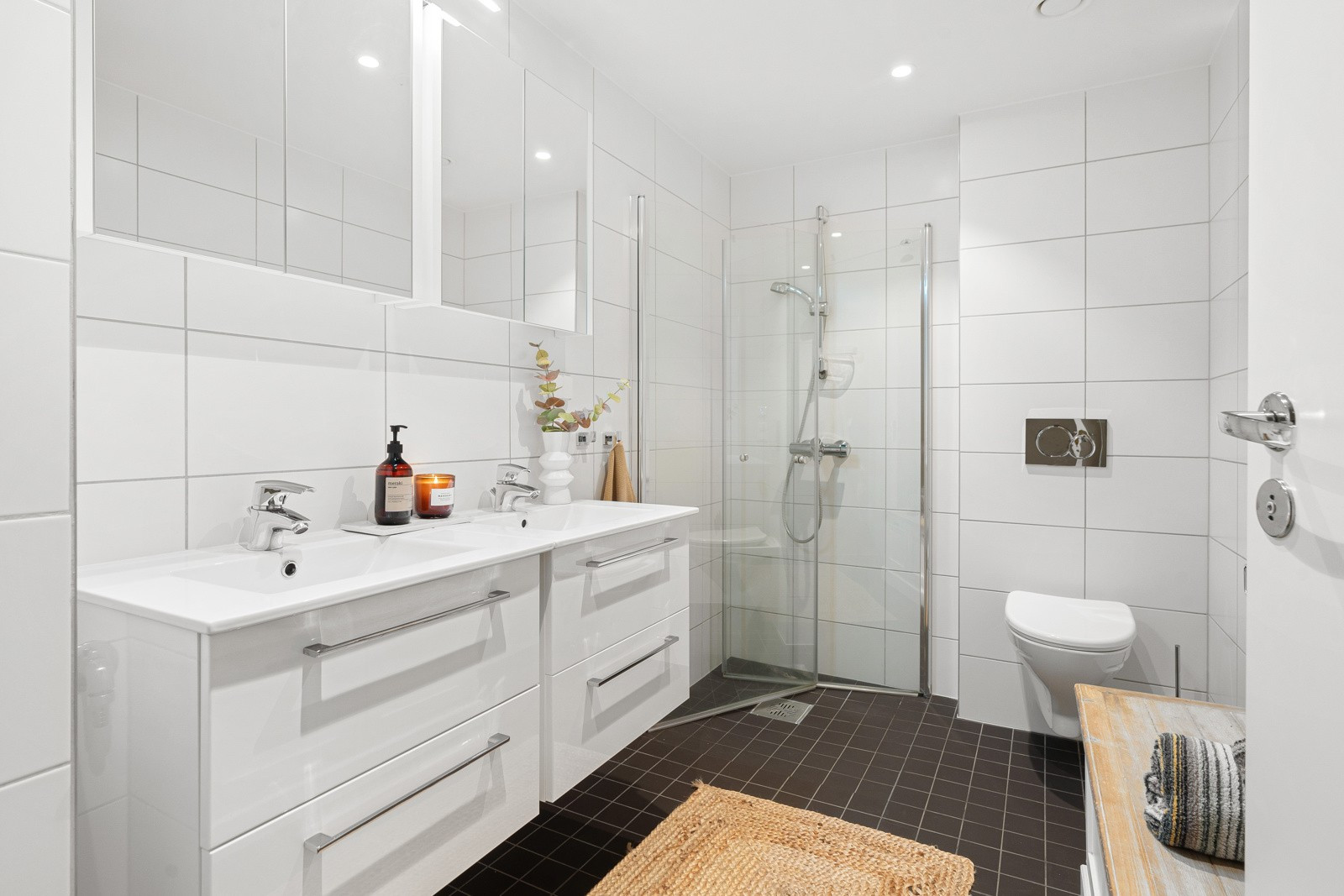 Badet i leiligheten er komplett flislagt og har hvit baderomsinnredning med dobbelvask. Her er det også montert downlights i tak.