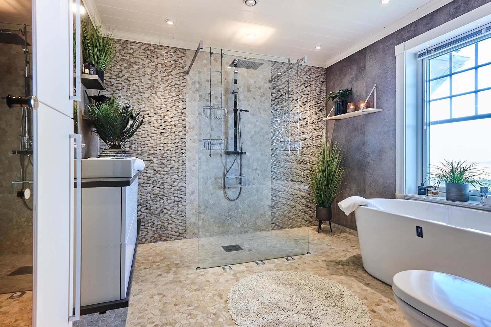 Forseggjort bad tilhørende hovedsoverom med lekre overflater, dusj og badekar. Galleribilde