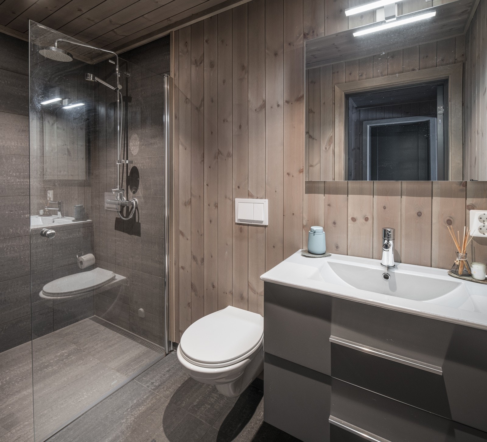 Bad 1. Lekkert bad med fliser på gulv og i dusjsone. Panel på vegg og tak. Galleribilde