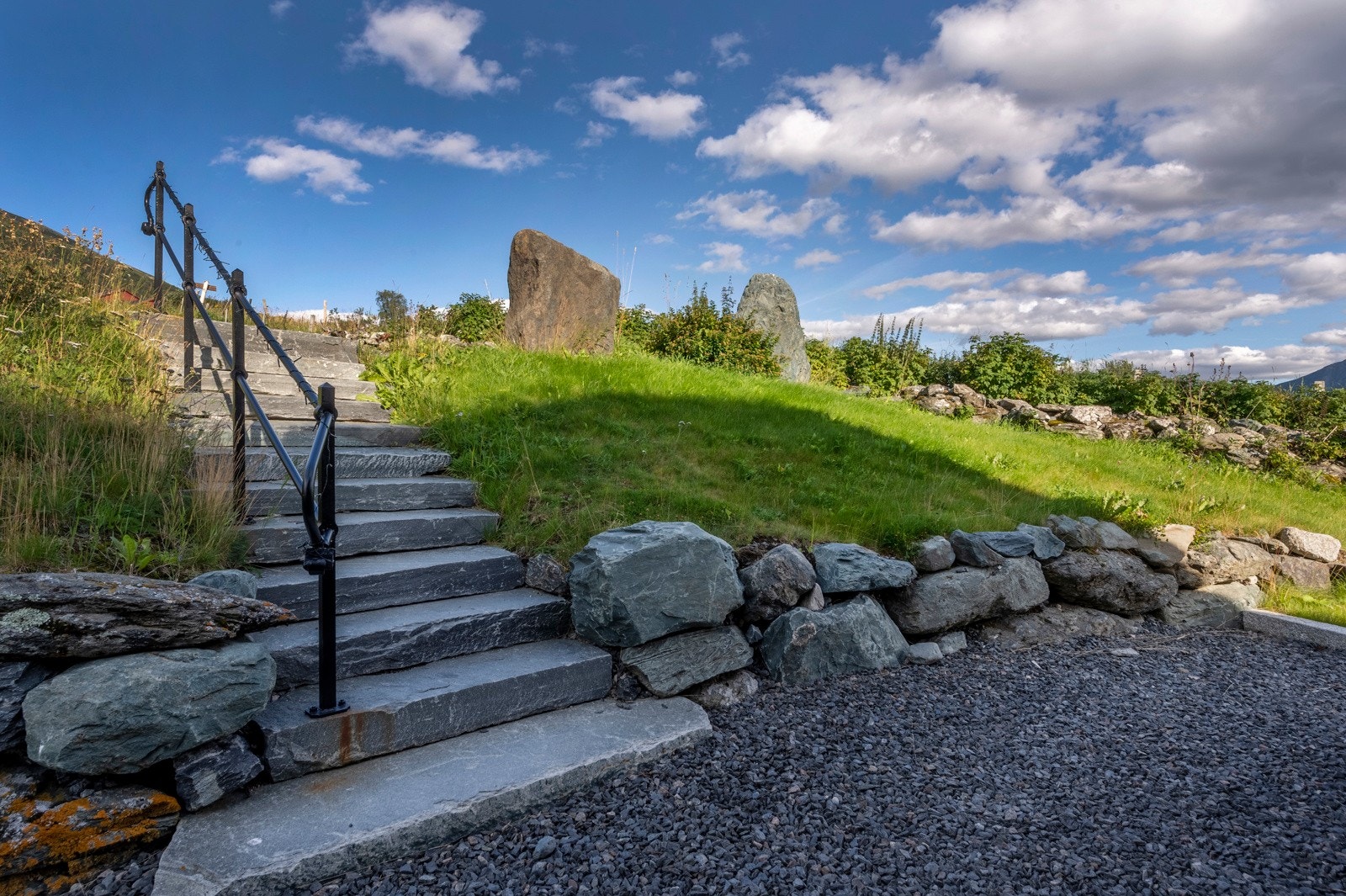 Det er etablert støttemur og trapp i naturstein samt nedsatt stabbesteiner mellom øvre og nedre nivå av tomten Galleribilde