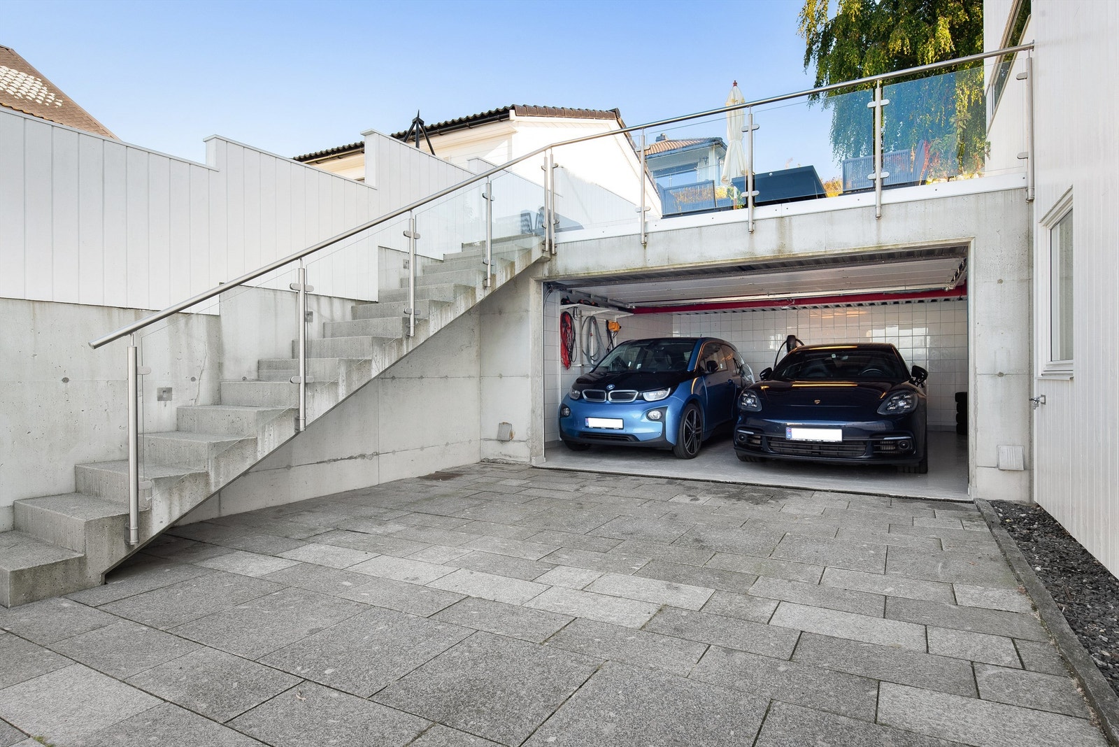 Den doble garasjen har el-bil lader (Tesla wallbox), flisebelagte vegger og epoxy gulv og ikke minst direkte adkomst inn i boligen. Tørr og trygg adkomst året rundt. Den stedstøpte betongtrappen har innfelt belysning og rekkverk i glass. Galleribilde