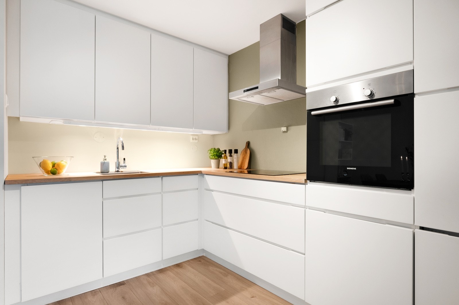 Moderne kjøkkeninnredning fra 2018 med hvite slette fronter og benkeplate av tre. Galleribilde