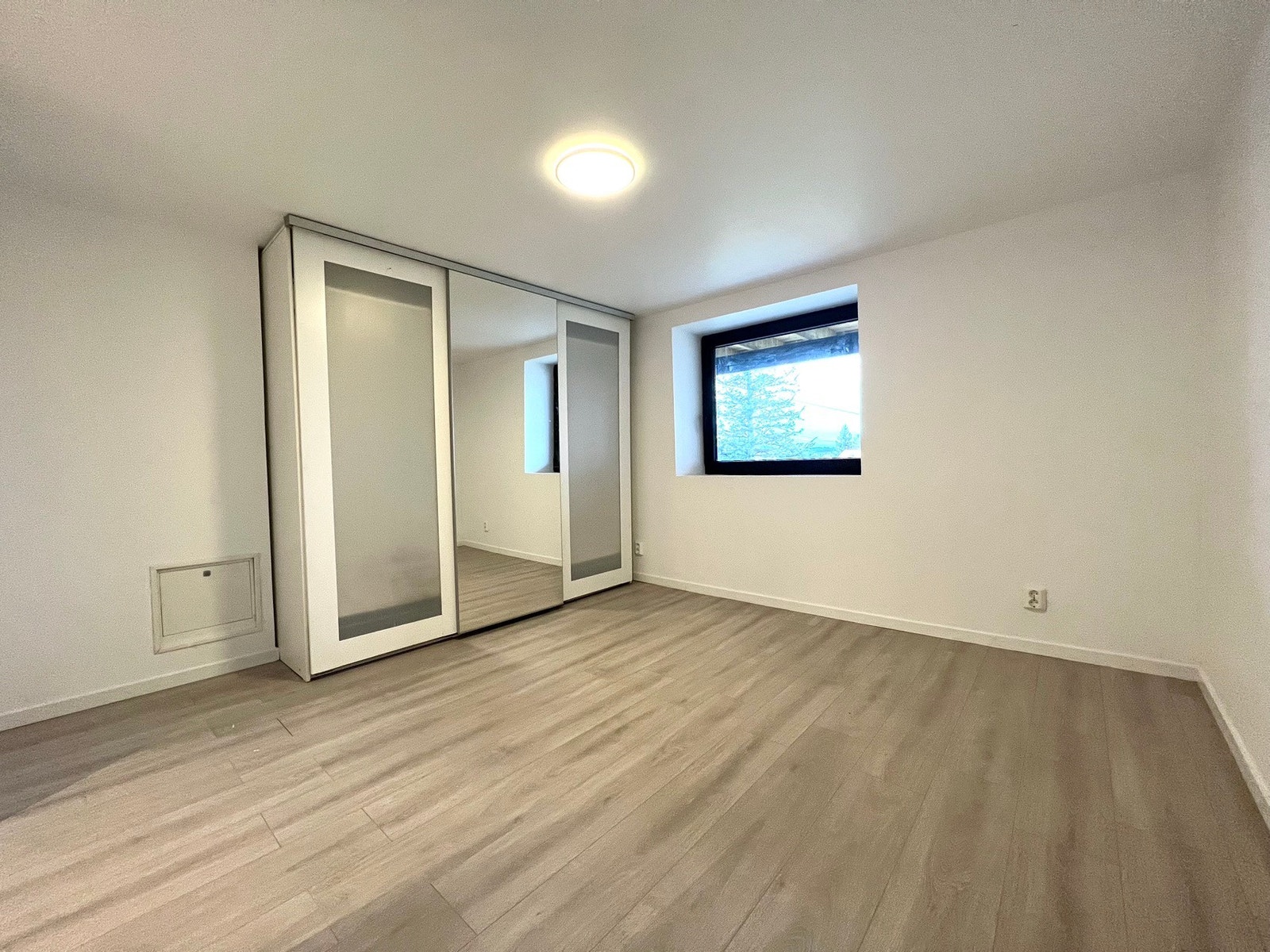 Lyst soverom med garderobeskap og plass til dobbeltseng Galleribilde