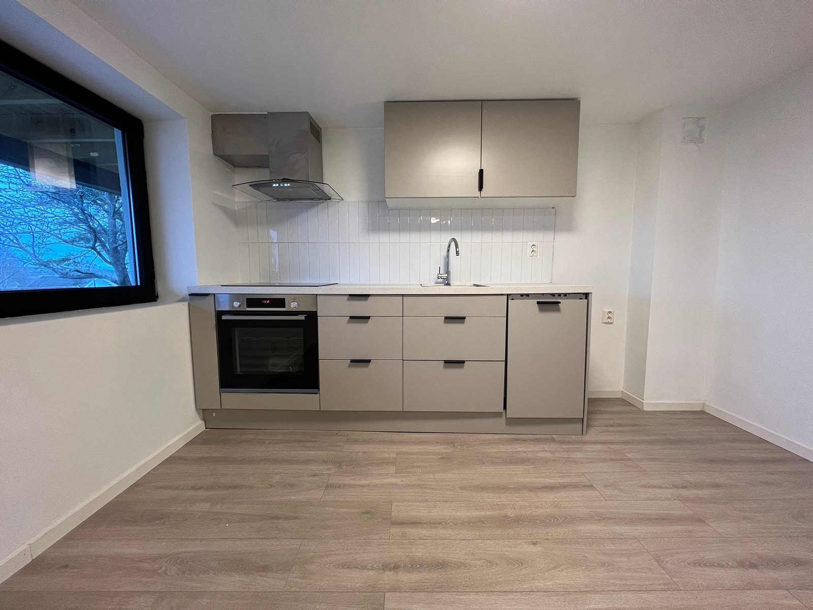 Beige, glatte fronter og fliser over benkeplate. Kjøleskap med fryser er lagt inn. Galleribilde