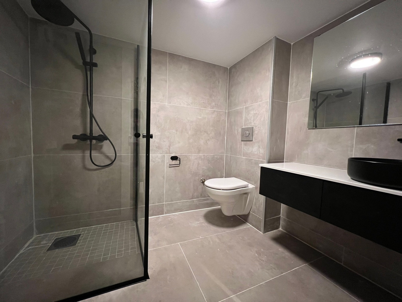 Flislagt bad med WC, servant med oppbevaring, dusj og vaskemaskin Galleribilde