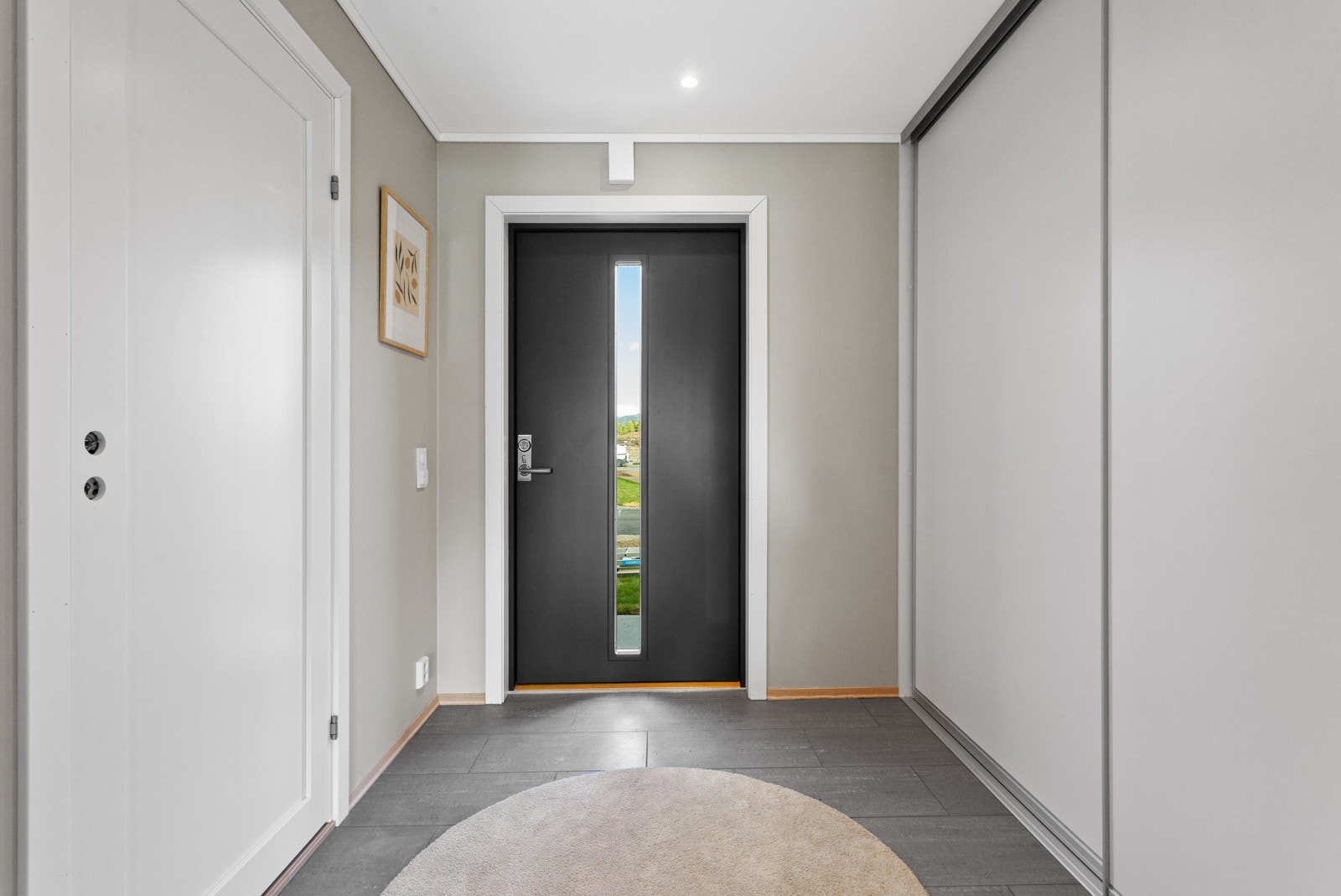 Romslig gang med skyvedørsgarderobe og dør inn til vaskerom/bad Galleribilde