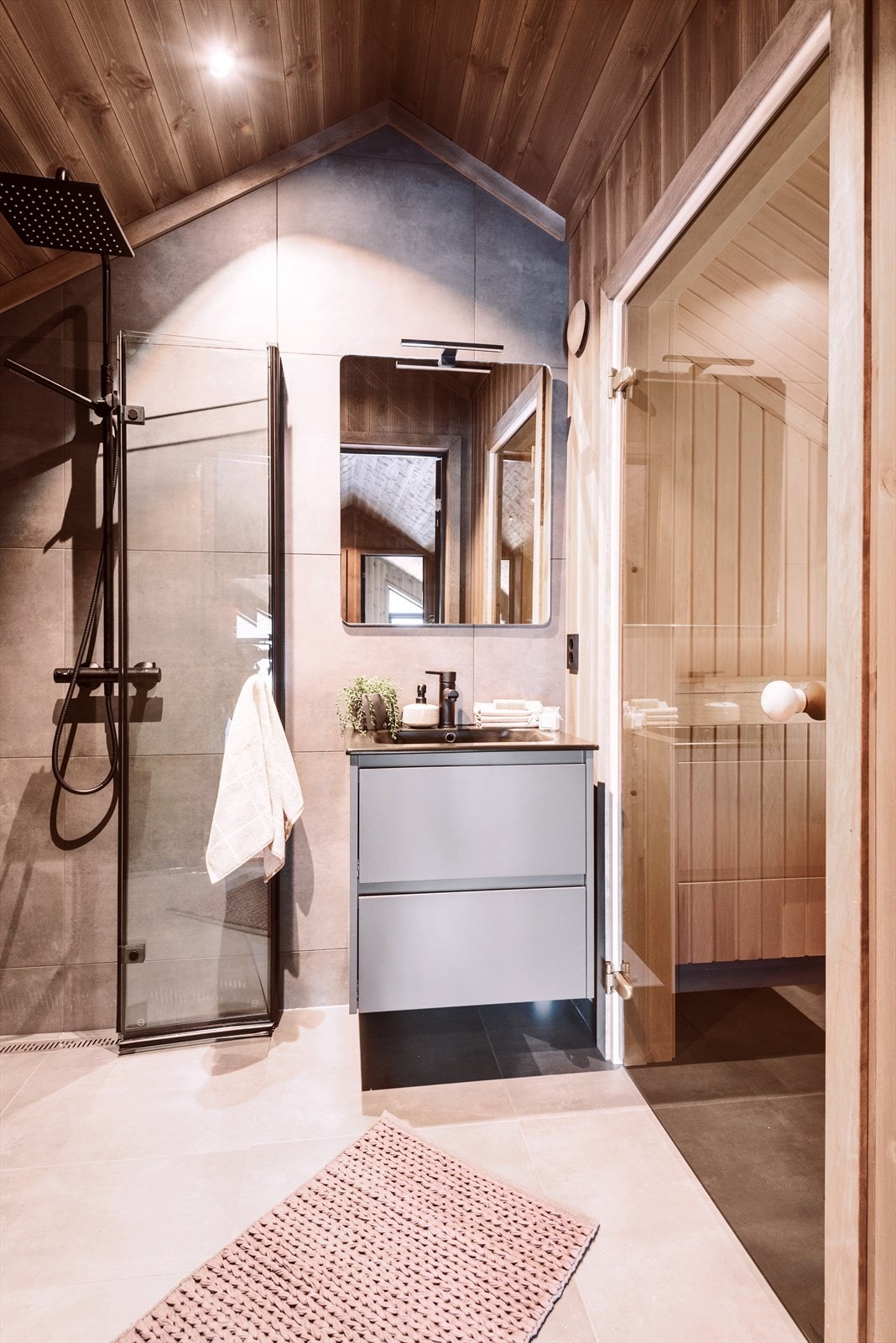 Baderom III i loftsetasjen har i tillegg en herlig badstue - perfekt etter en lang dag på ski. Baderomsinnredningen er pga. feil størrelse erstattet med en matt svart (eikestruktur) innredning med hvit servant Galleribilde