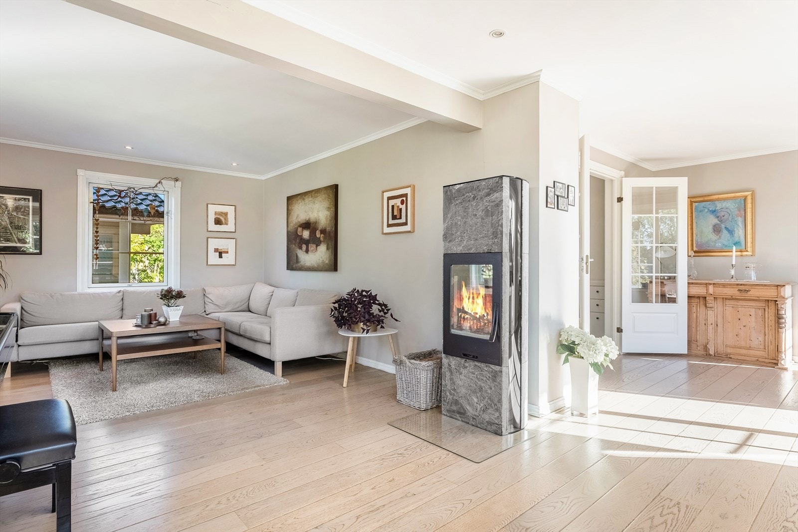 Stuen er holdt i lyse farger -og lyst interiør. Vedovn kledd med kleberstein gir god og jevn varme i rommet Galleribilde