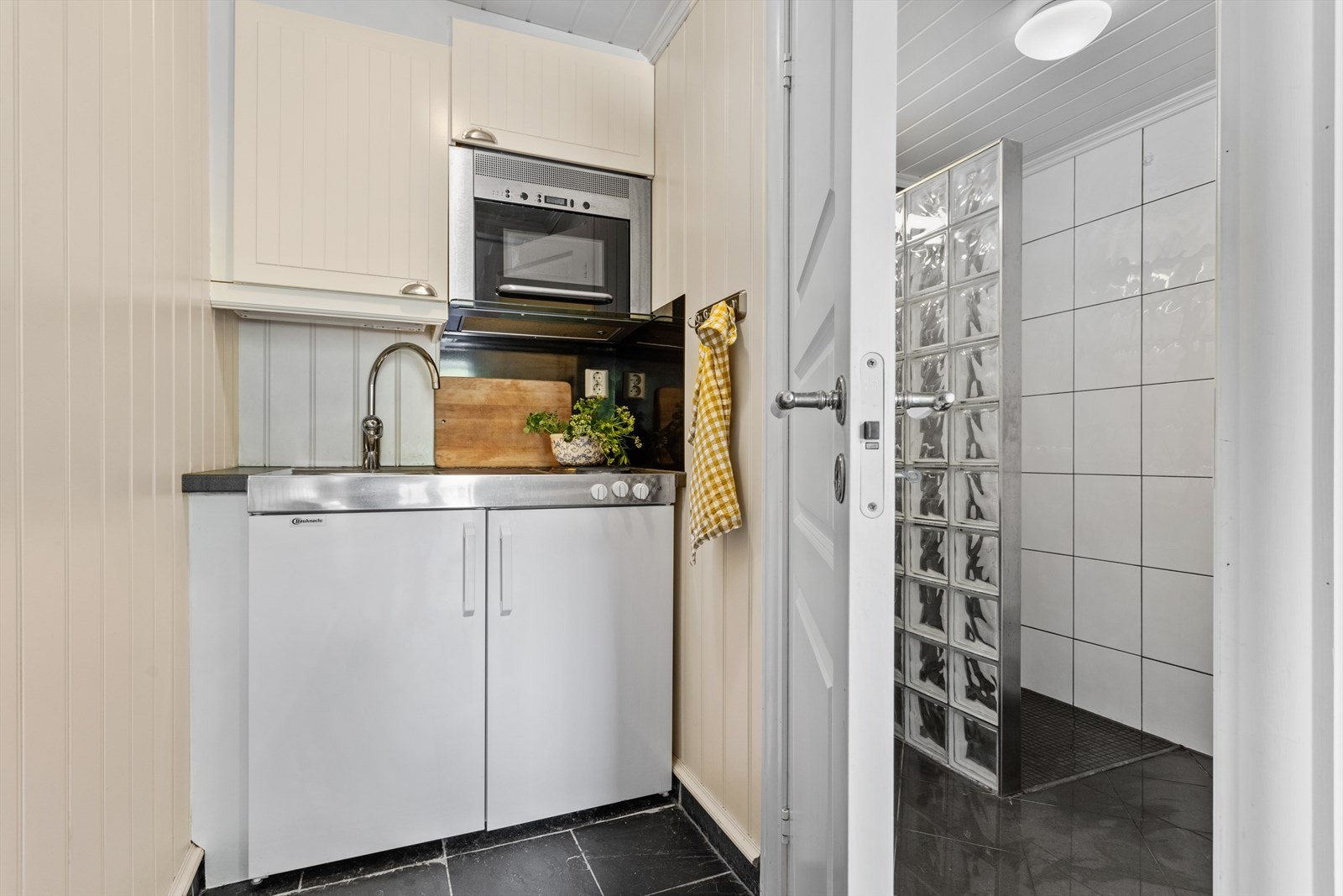 Kjøkkeninnredningen har profilerte fronter, laminert benkeplate og integrert kjøleskap, stålvask og to kokeplater. Galleribilde