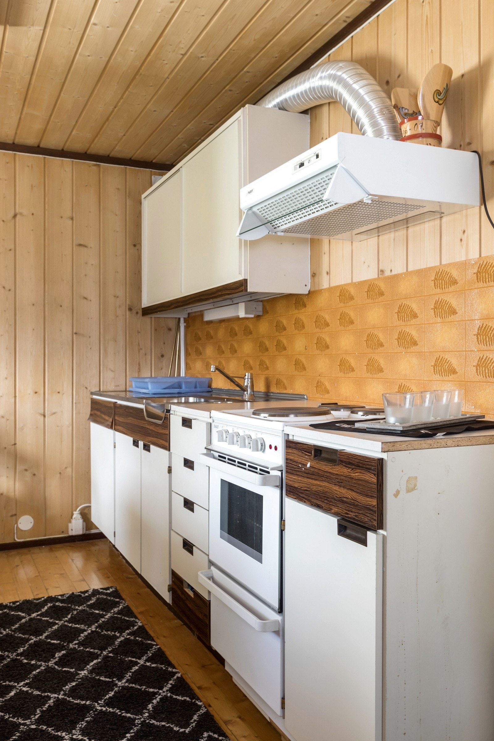 Kjøkken har en eldre innredning med under- og overskap i laminat/finerte plater. Oppvaskbenk i rustfritt stål samt ventilator. Galleribilde