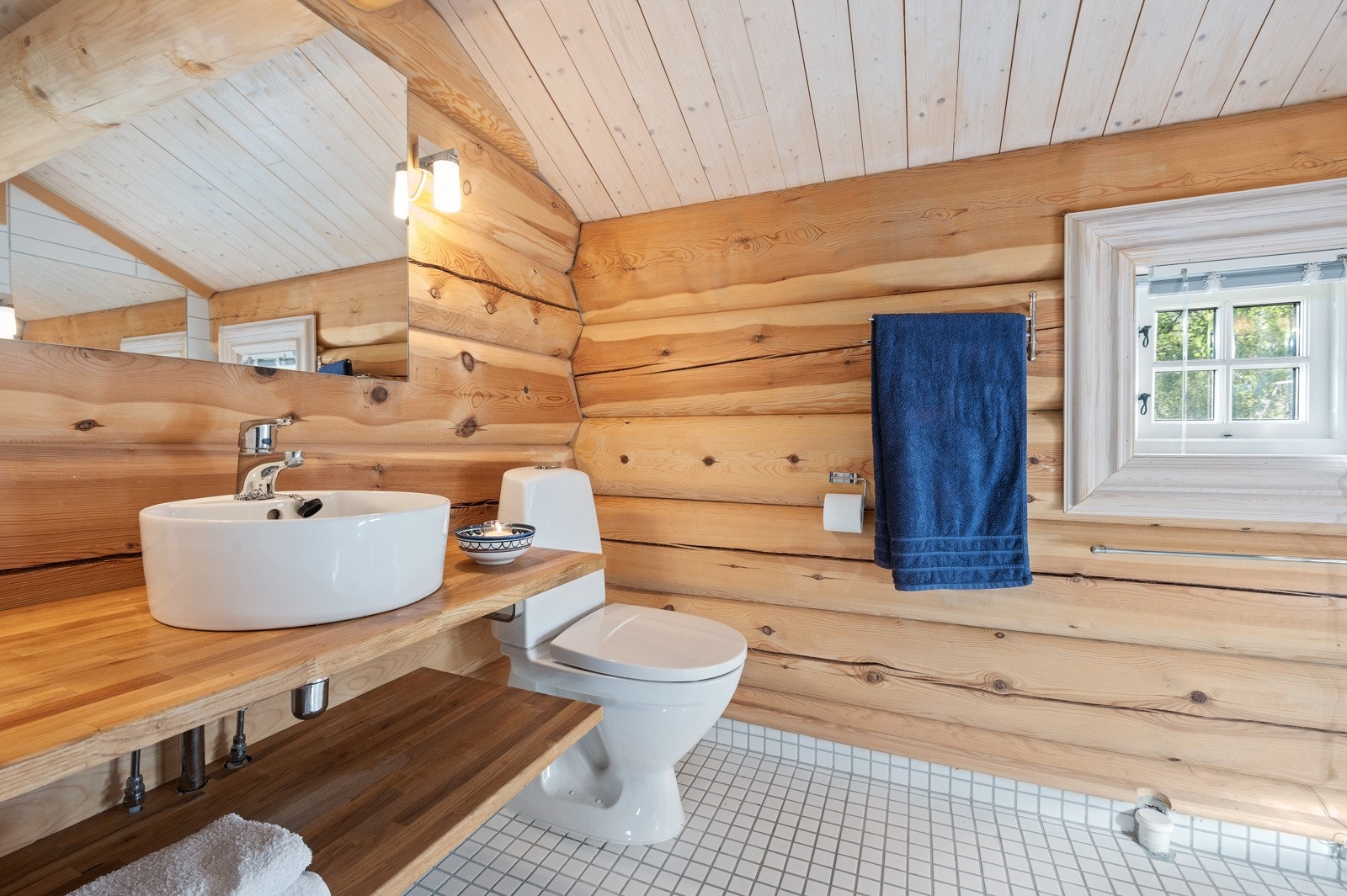 Bad I er innredet med toalett, dusjsone med dobble glassdører og servant. Det er varme i det flislagte gulvet og opplegg for vaskemaskin. Galleribilde