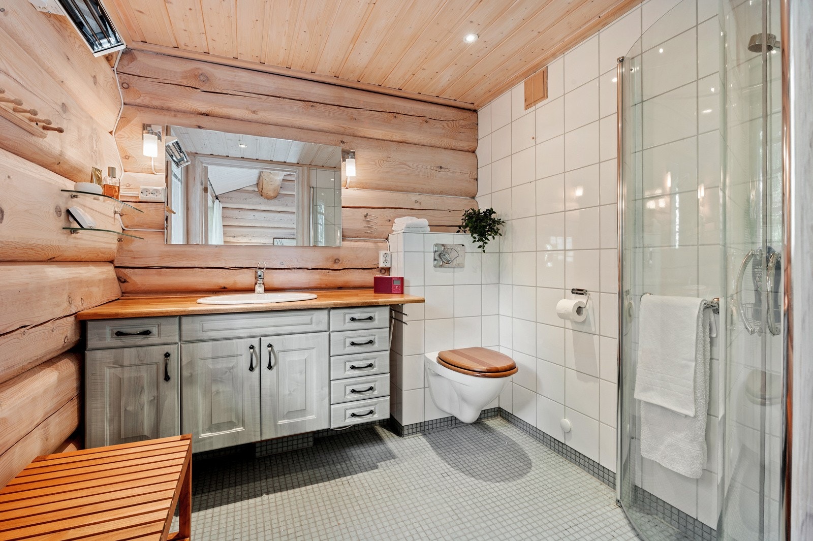 Badet ligger i tilknytning til hovedsoverommet og blir dermed privat. Badet har flislagt gulv med mosaikkdetaljer, hvite veggfliser og spotbelysning i taket. Galleribilde