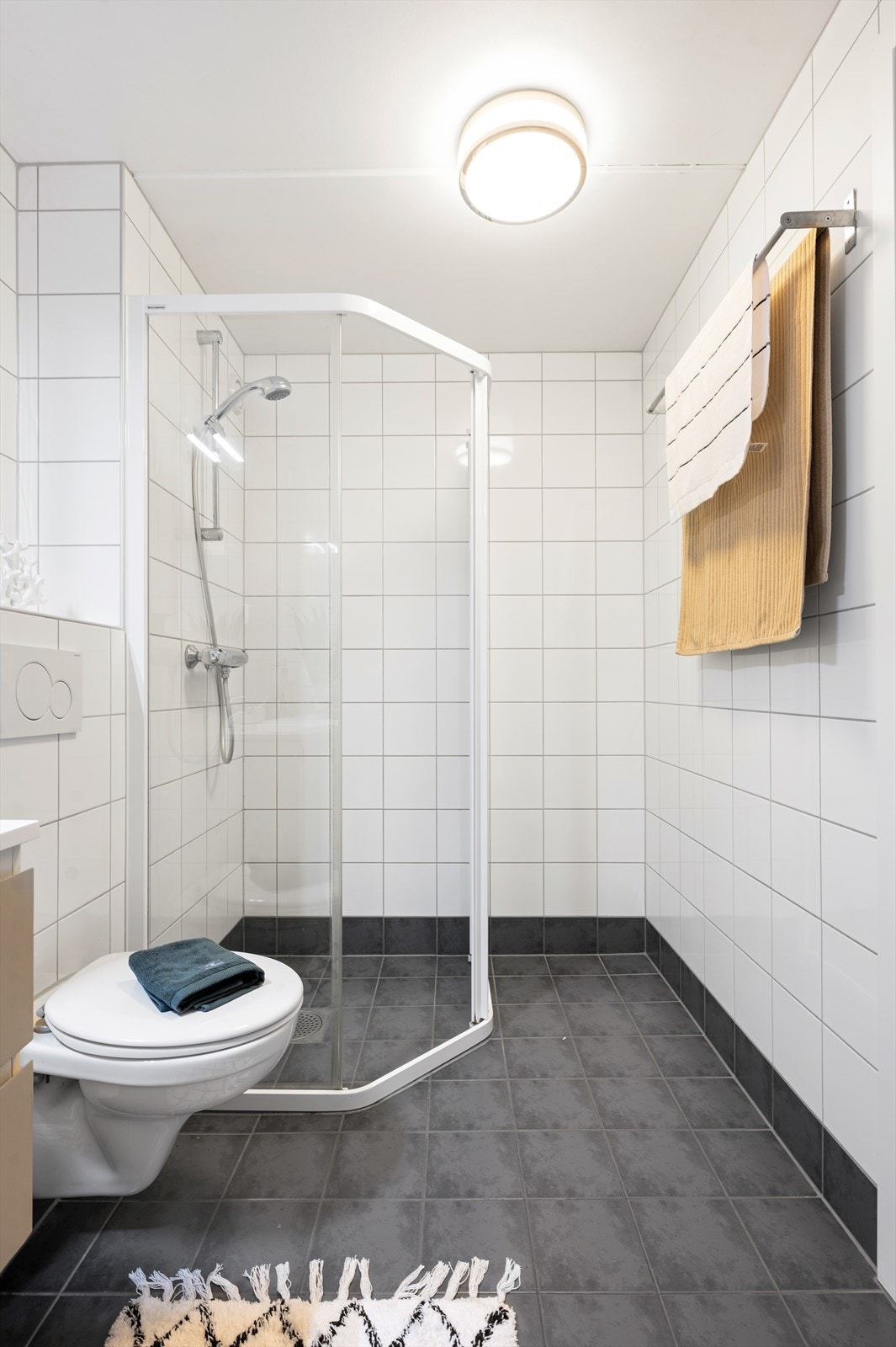 Badet er innredet med vegghengt servantskap med skuffer, speil, overlys, dusj på gulv med innfellbare dører og vegghengt toalett Galleribilde